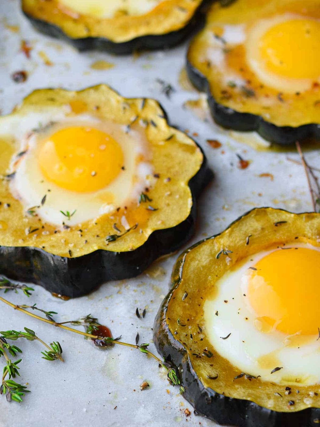 Angled view of acorn squash egg in a hole with thyme.
