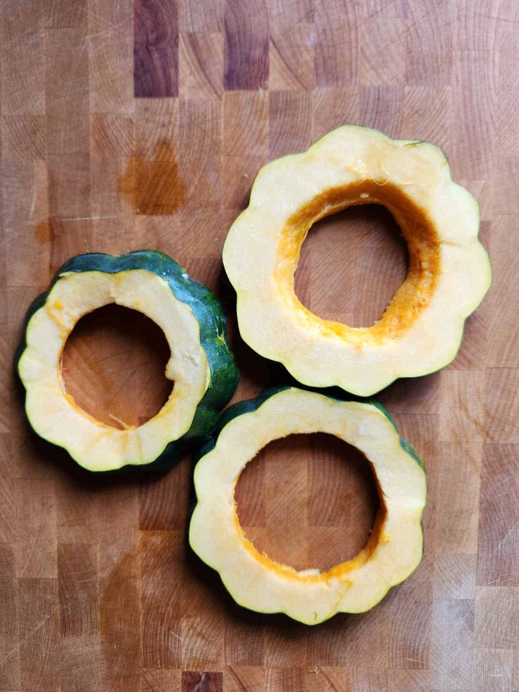 Three acorn squash rings on a cutting board.