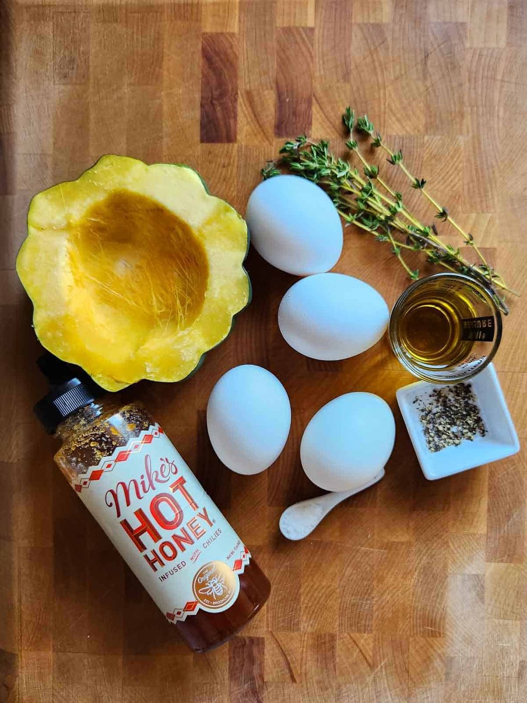 Ingredients for acorn squash egg in a hole on a cutting board.