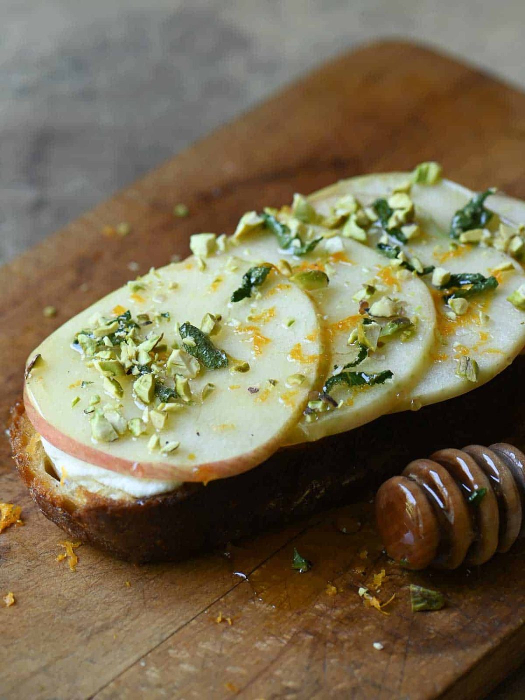 Apple toast with ricotta, honey and nuts on a cutting board.