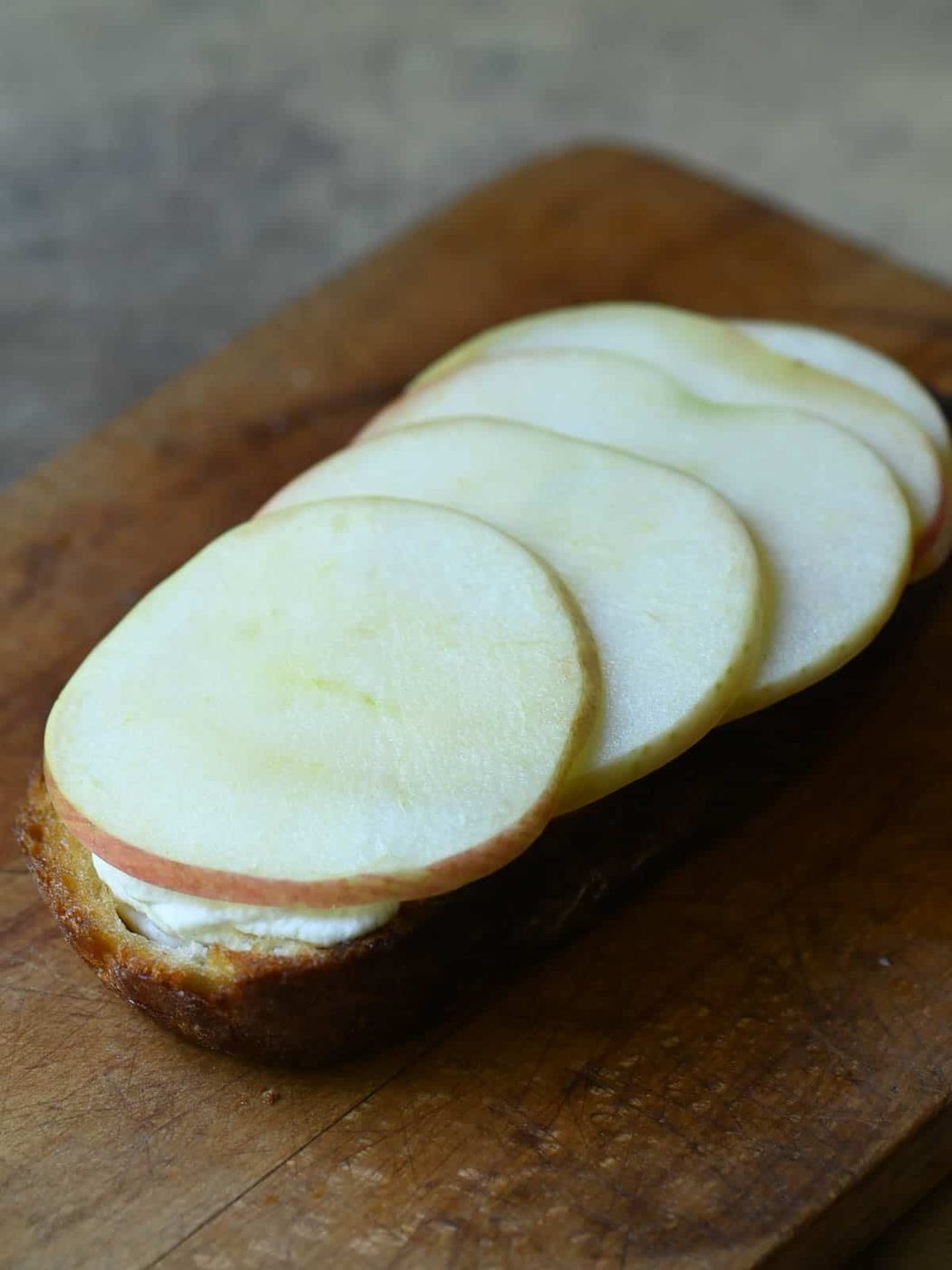 Apples and ricotta on toast in a cutting board.