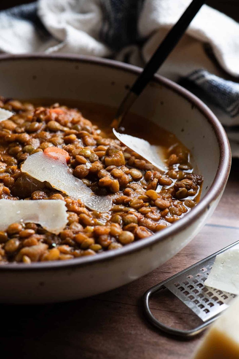 Close-up of bacon lentil soup in a beige bowl.