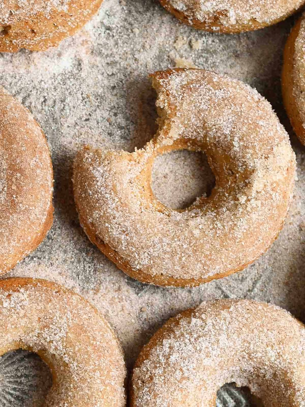 A bite of an apple donut taken out on a tray.
