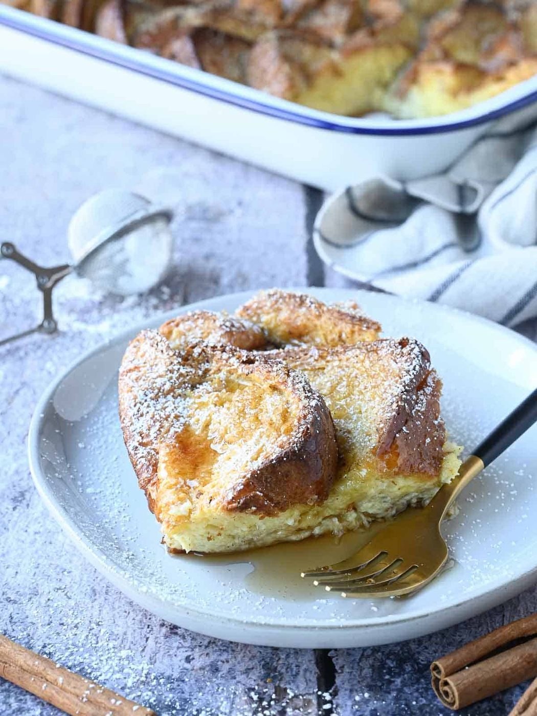 A slice of baked Brioche French toast on a white plate.