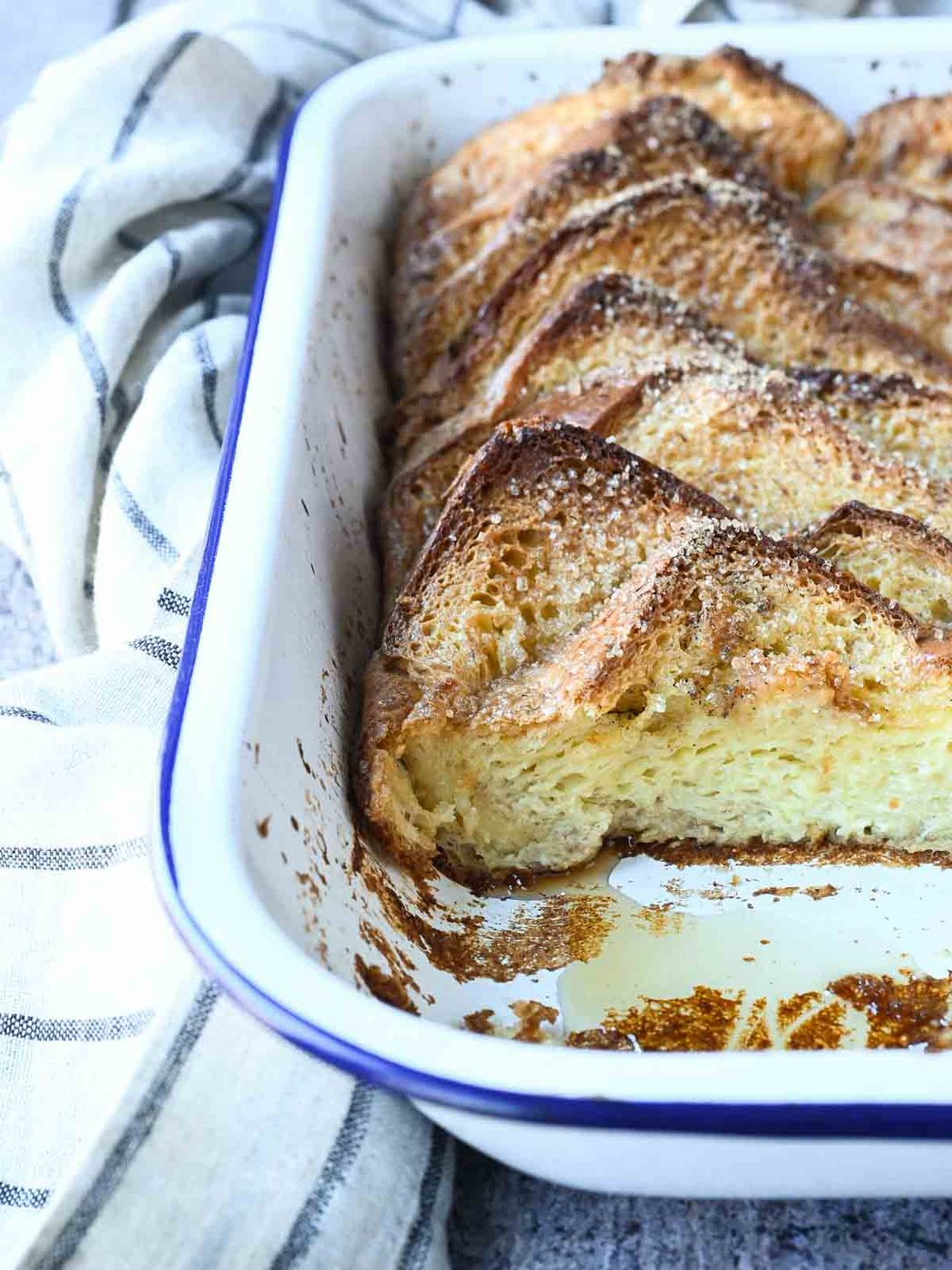 Baked French toast in a white pan, with a piece taken out.