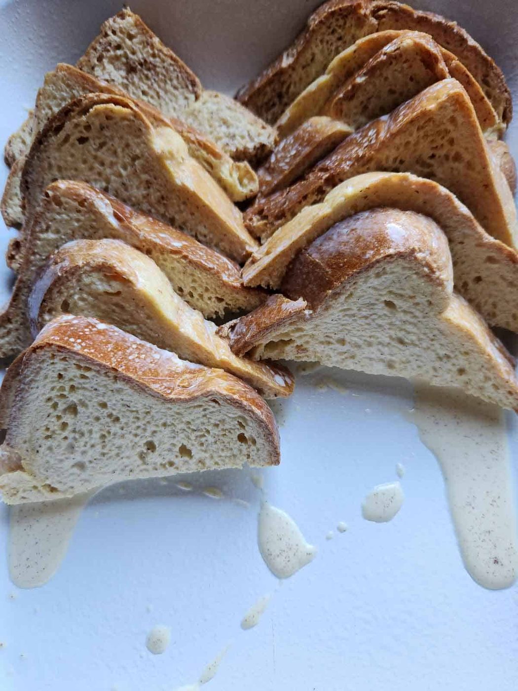 French toast casserole bread slices in a white pan.