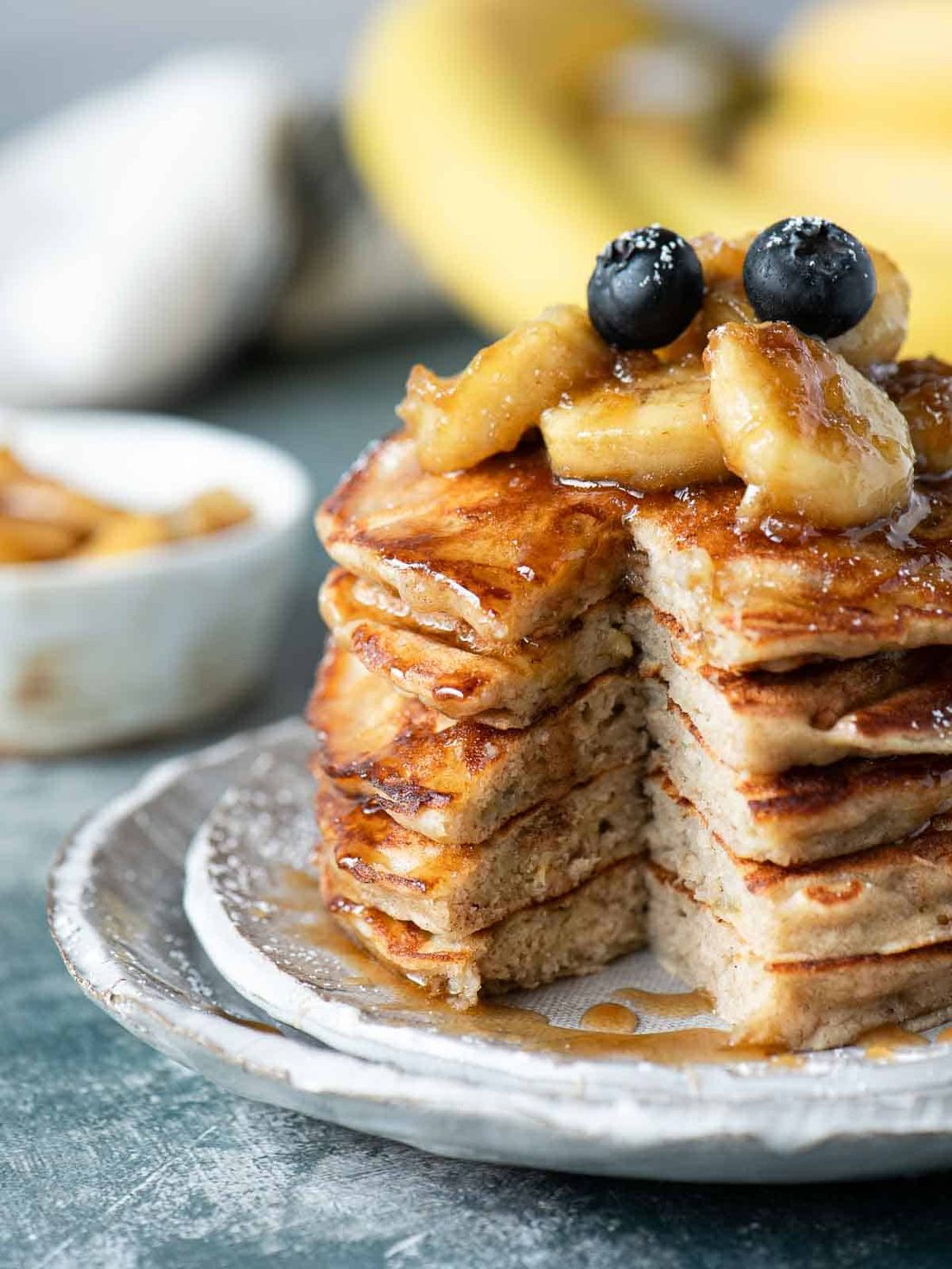 A stack of banana bread pancakes cut open to see inside with bananas on top.