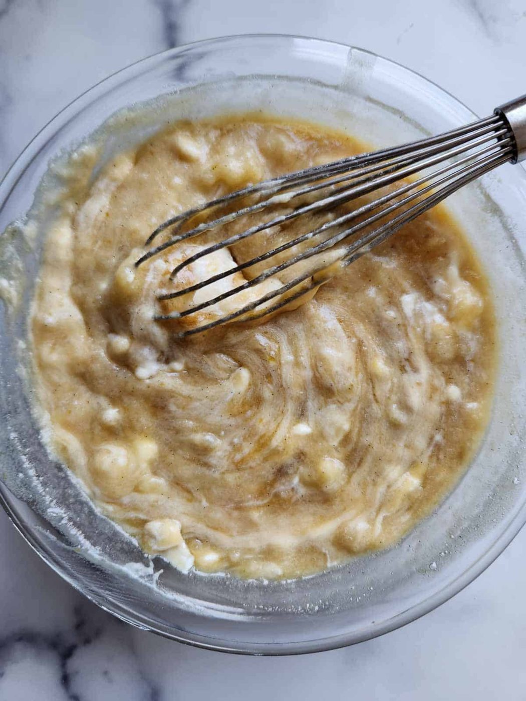 Banana muffin batter in a clear bowl.