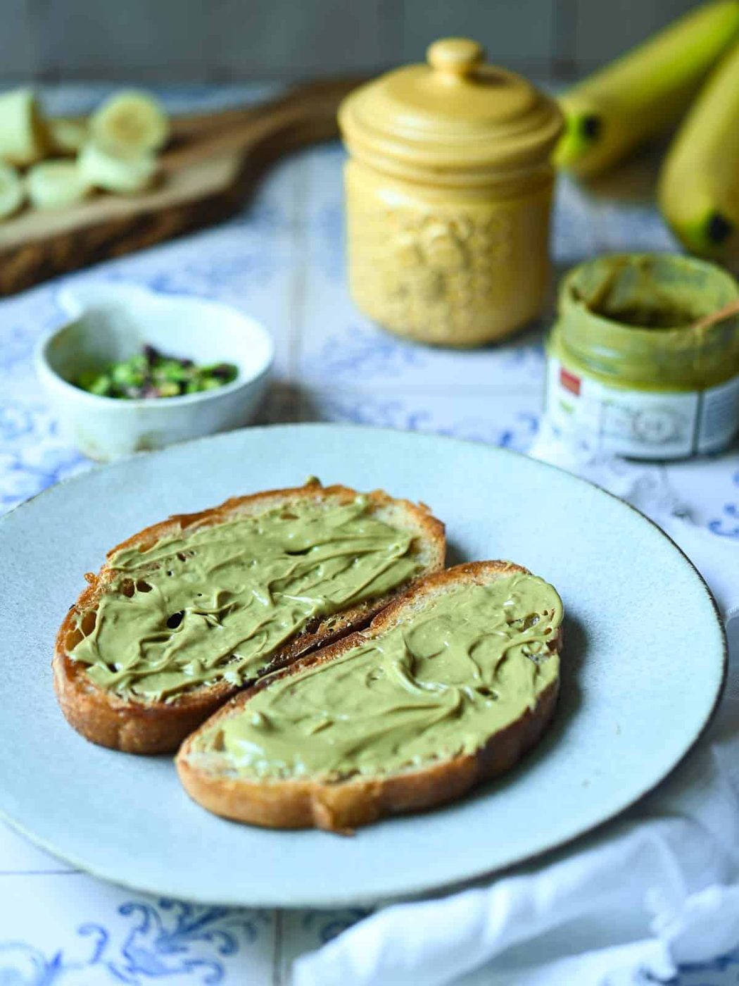 Two slices of toast with pistachio spread on a white plate.