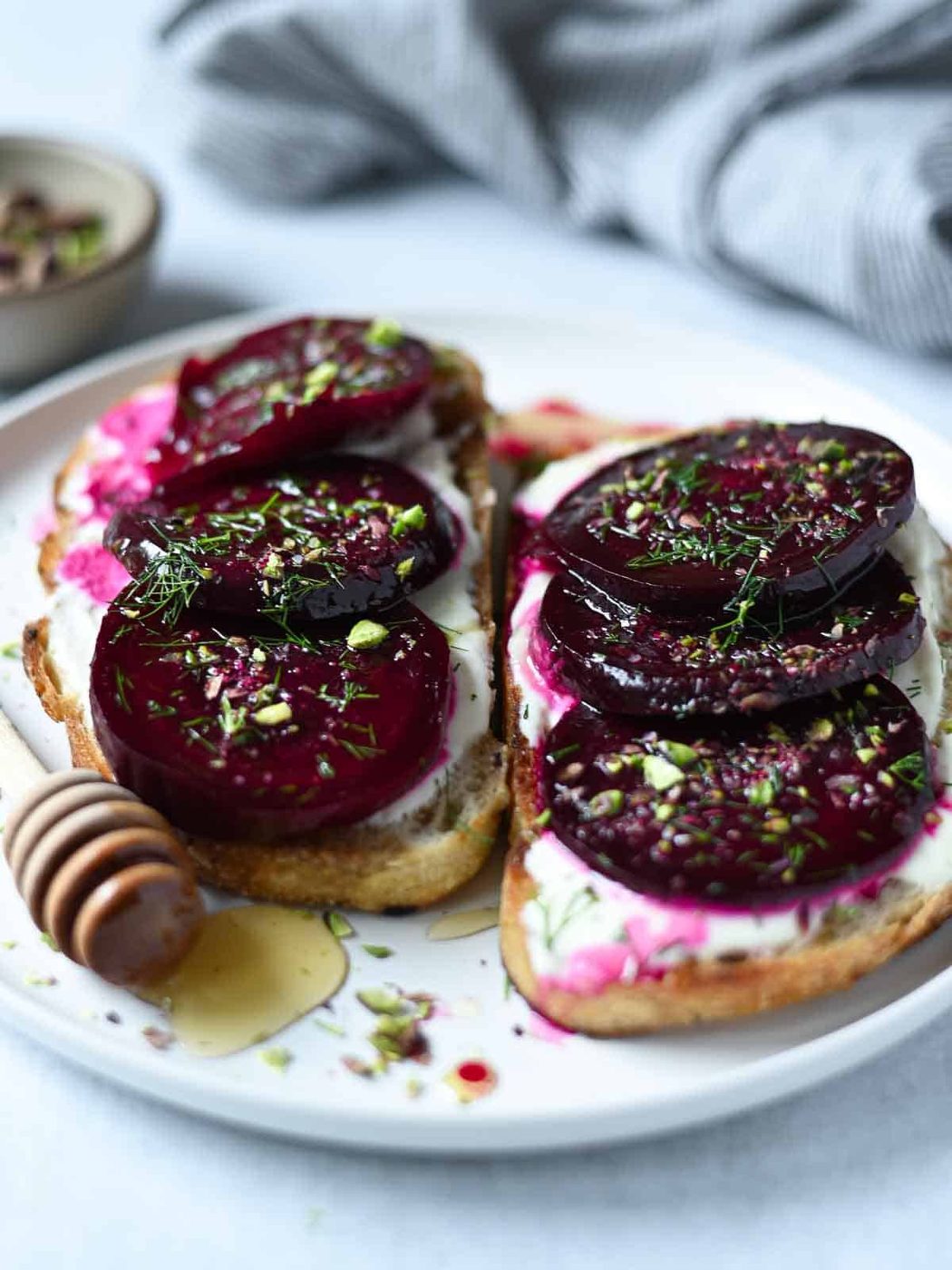 Two slices of beet toast on a white plate with a honey drizzle.