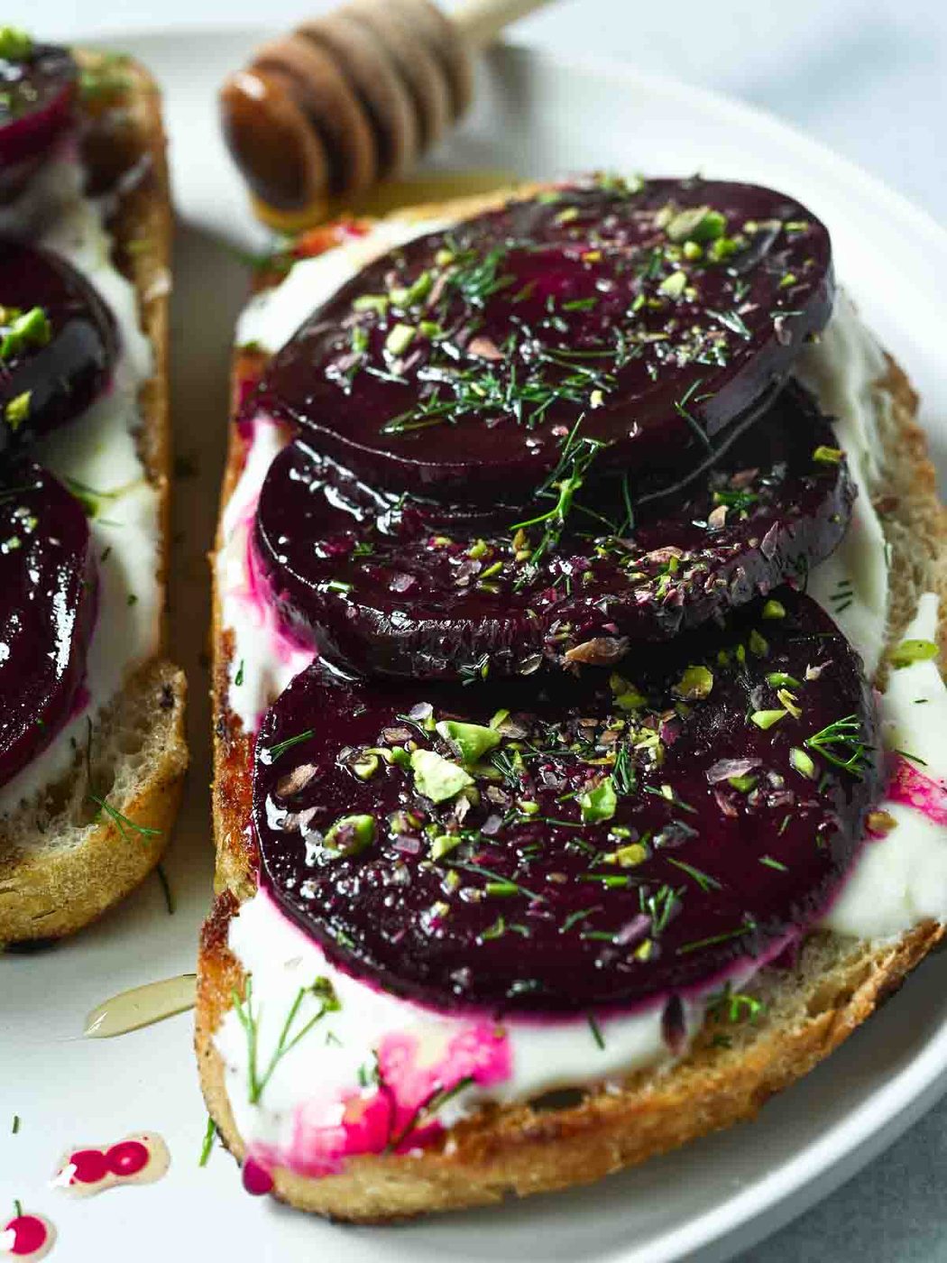 Close-up of sliced beets on toast on a white plate.