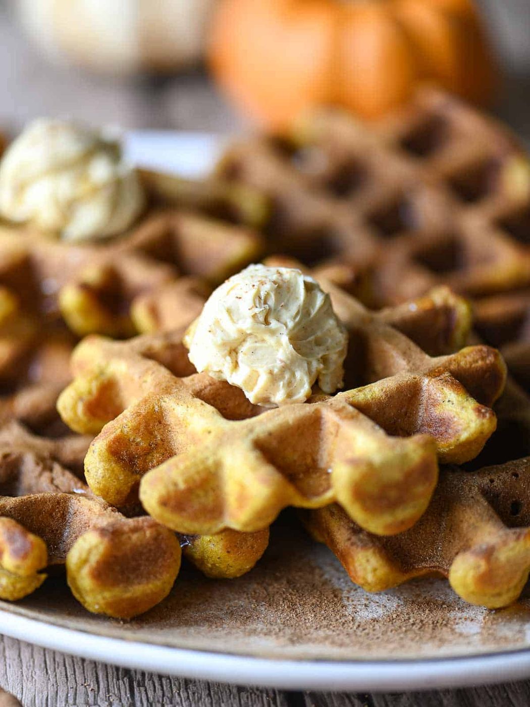 Eye level pumpkin waffles with butter on top.