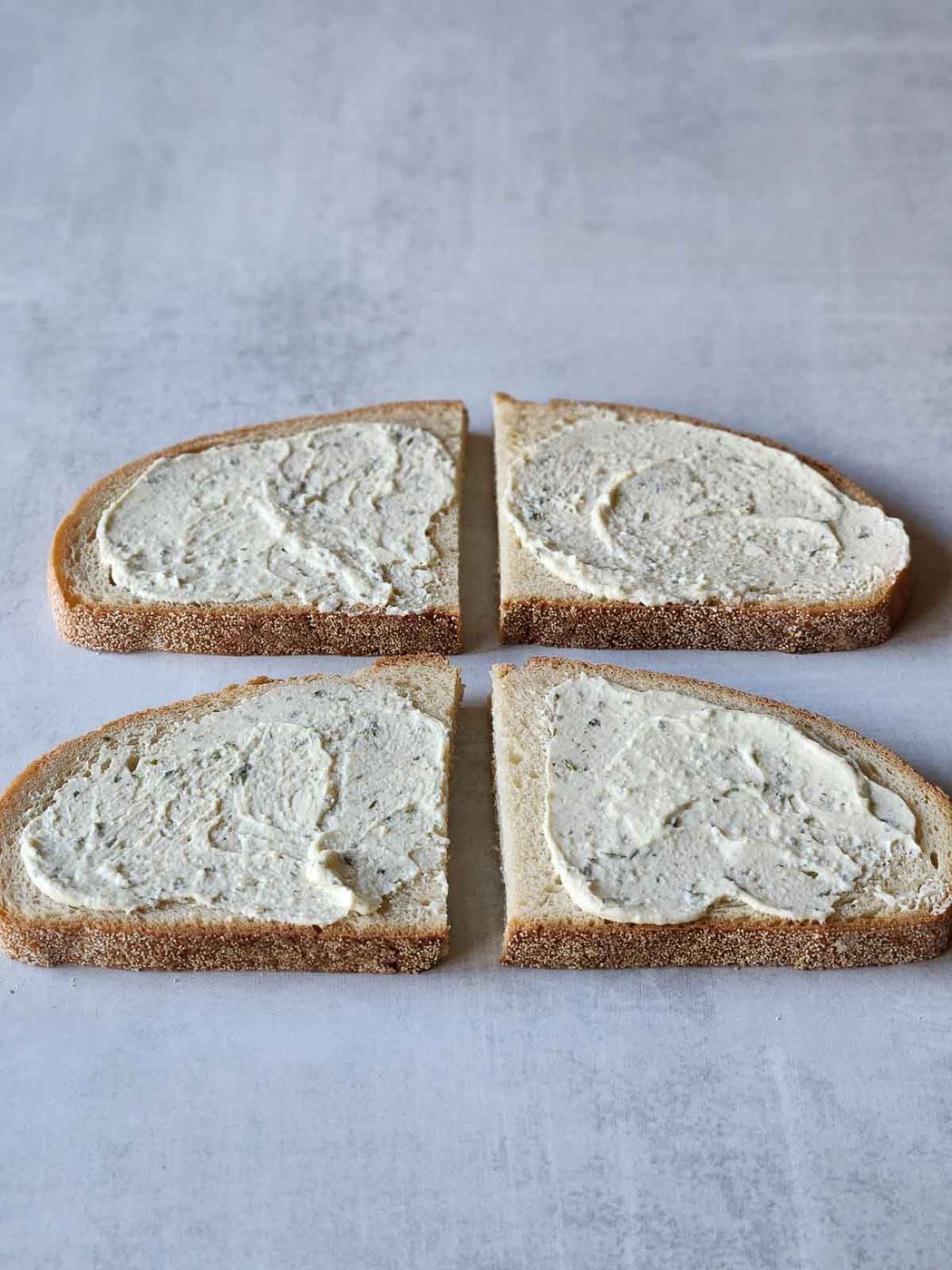 Four slices of bread with Boursin cheese spread on the top.