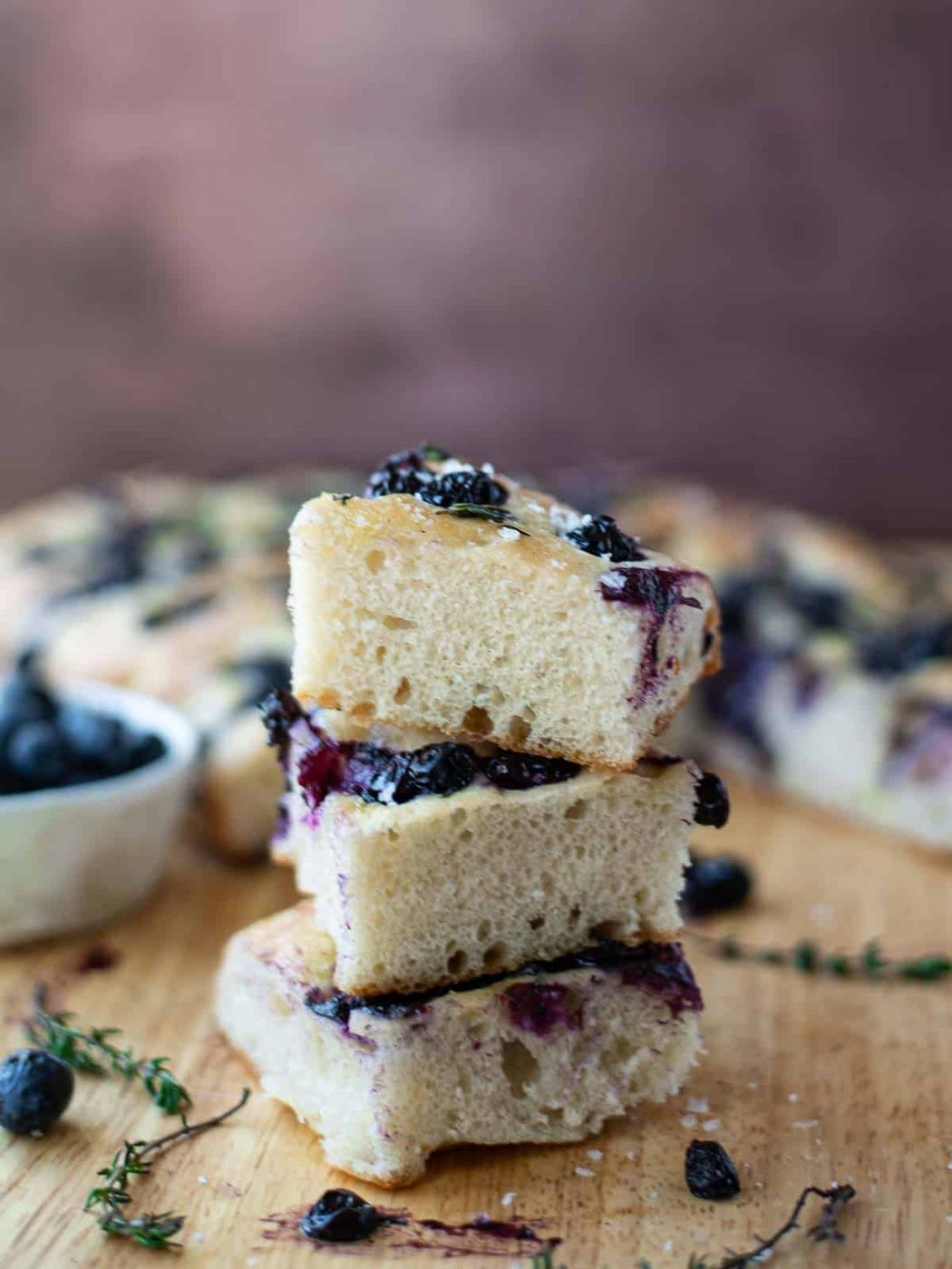 Three slices of focaccia piled on top on each other on a wooden board.
