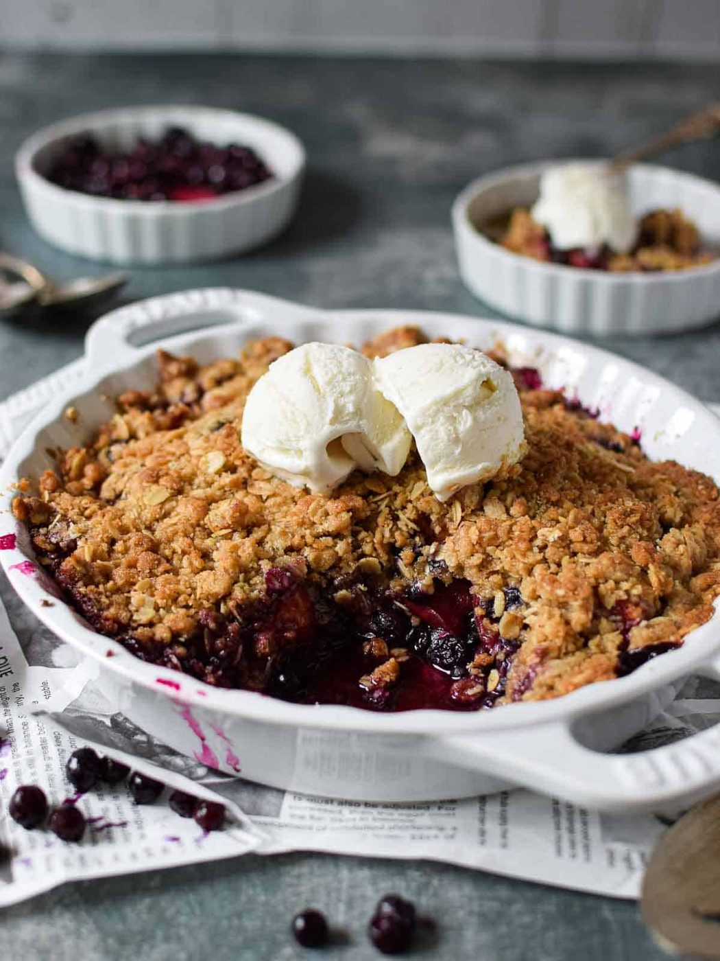 Angled view of blueberry crisp in a white pie plate.