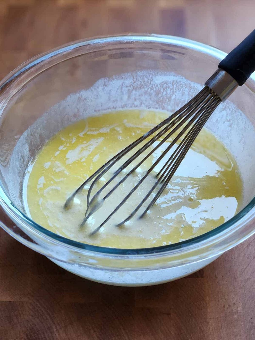 Wet ingredients in a clear bowl with a whisk.
