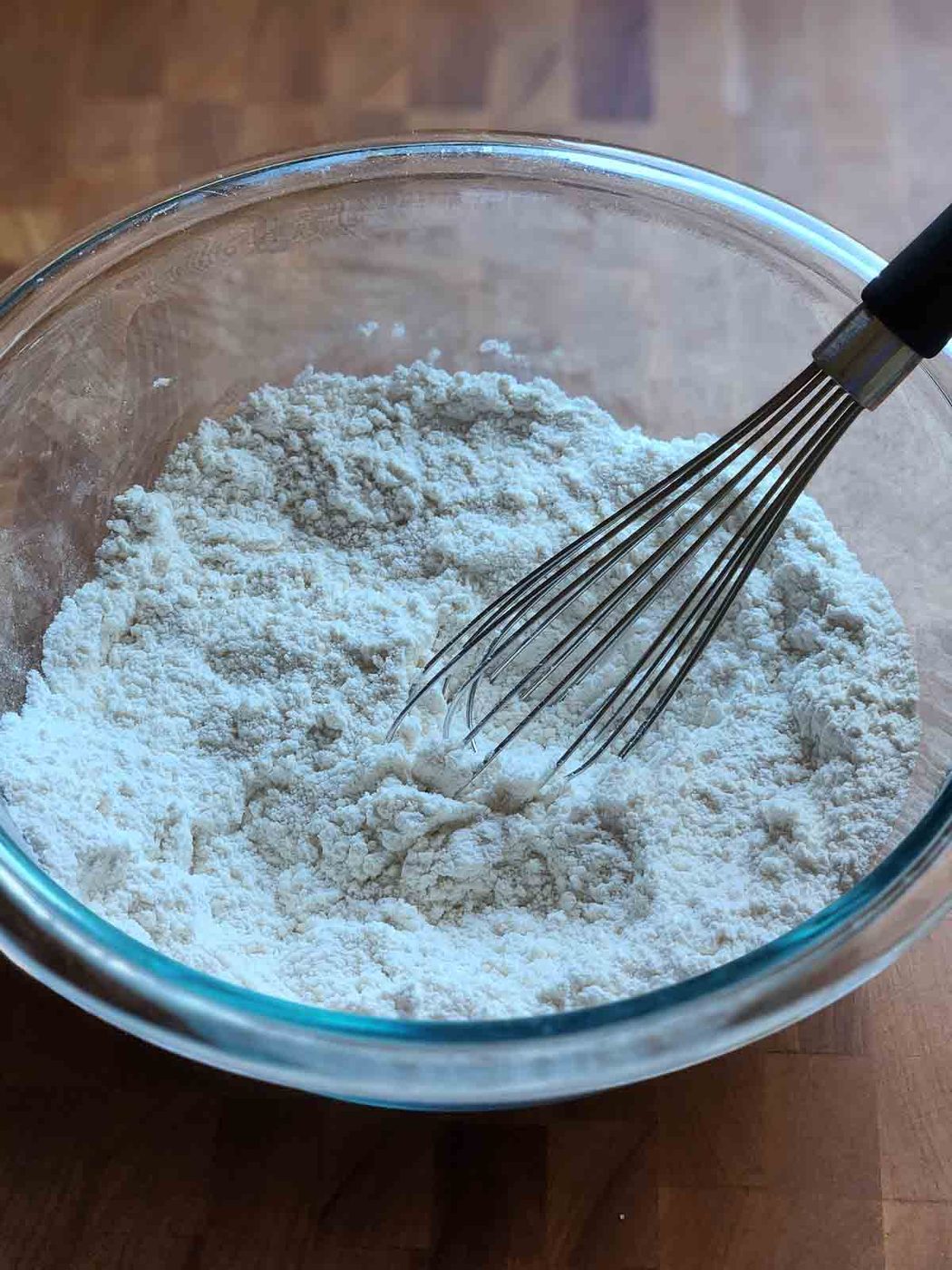 Dry ingredients in a clear bowl with a whisk.