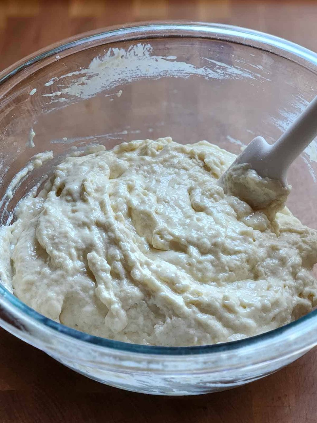 Pancake batter in a clear bowl with a spatula.