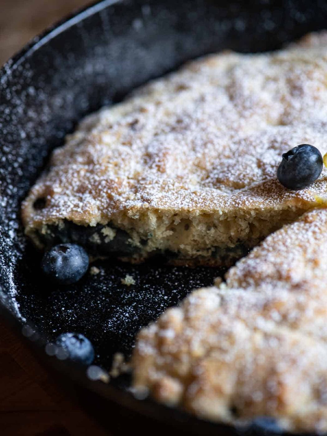 Close-up of a skillet pancake with a slice taken out.