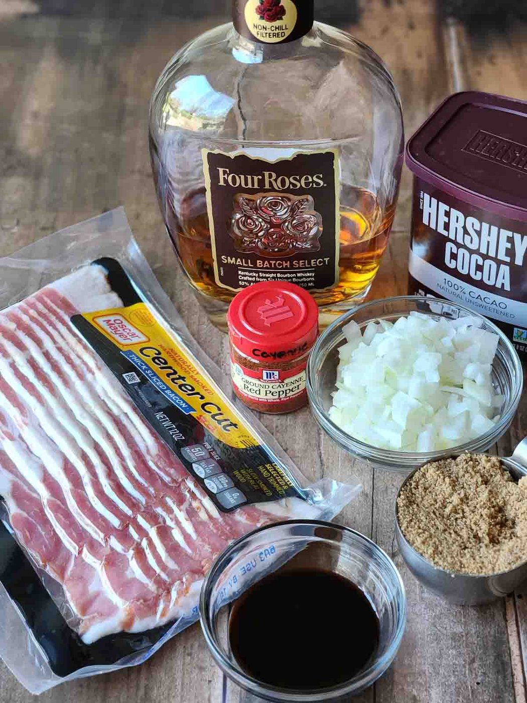 Ingredients for bourbon bacon jam on a wood surface.