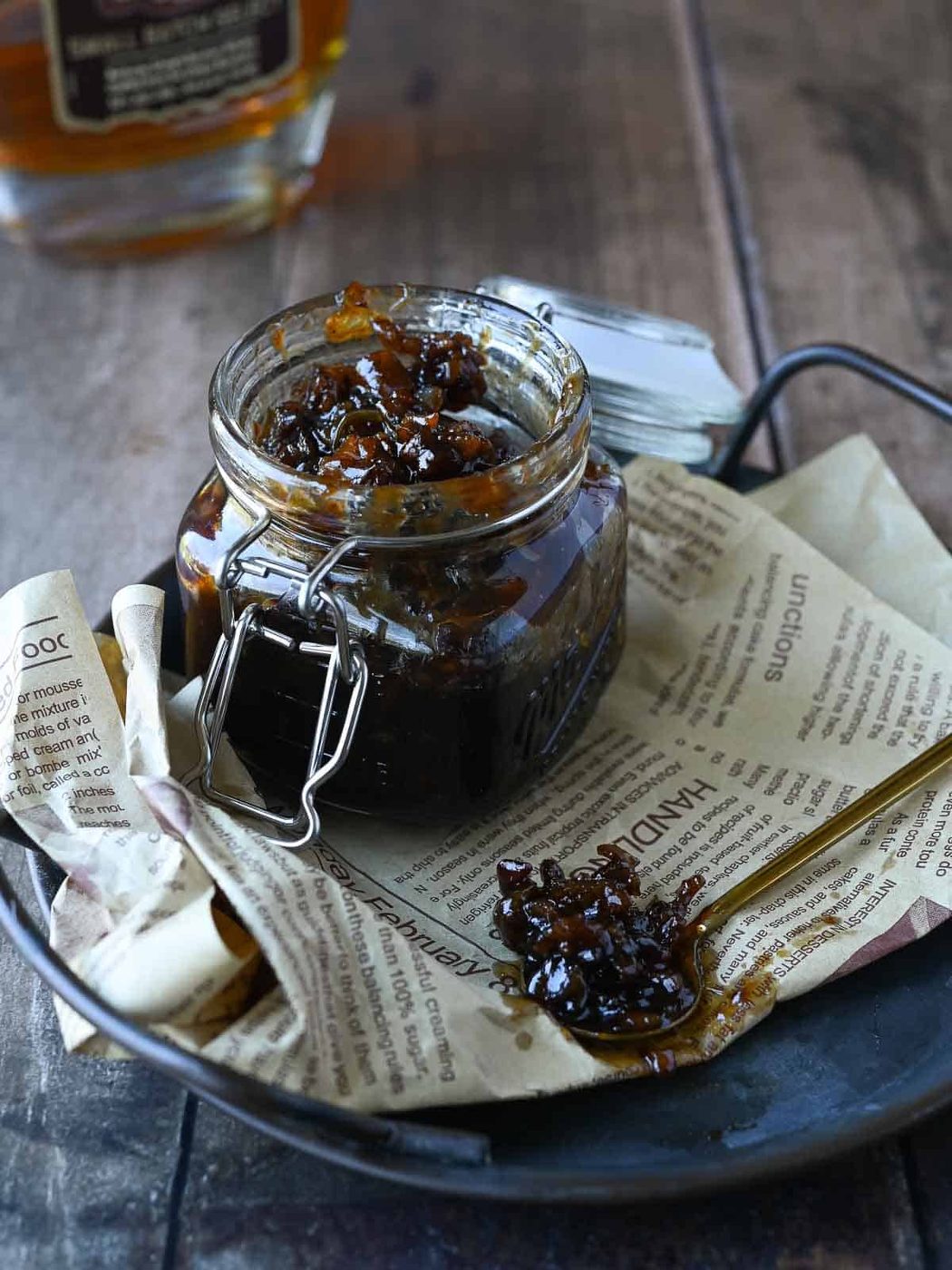 Bourbon and bacon jam in a clear jar with some on a spoon.