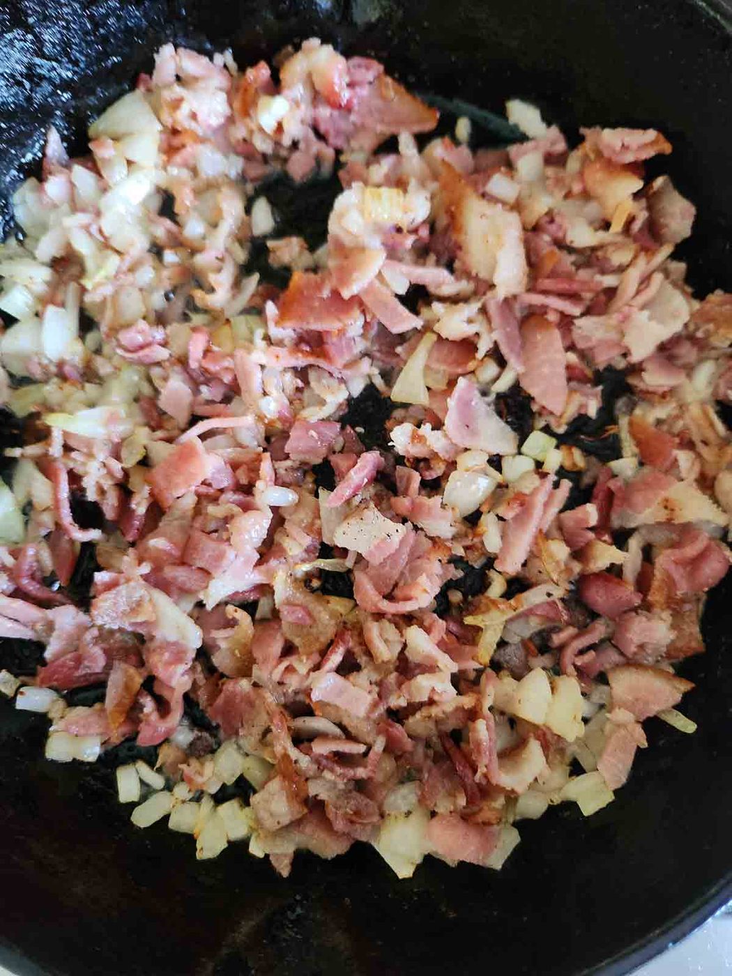 Sautéed onions and bacon in a cast iron skillet.