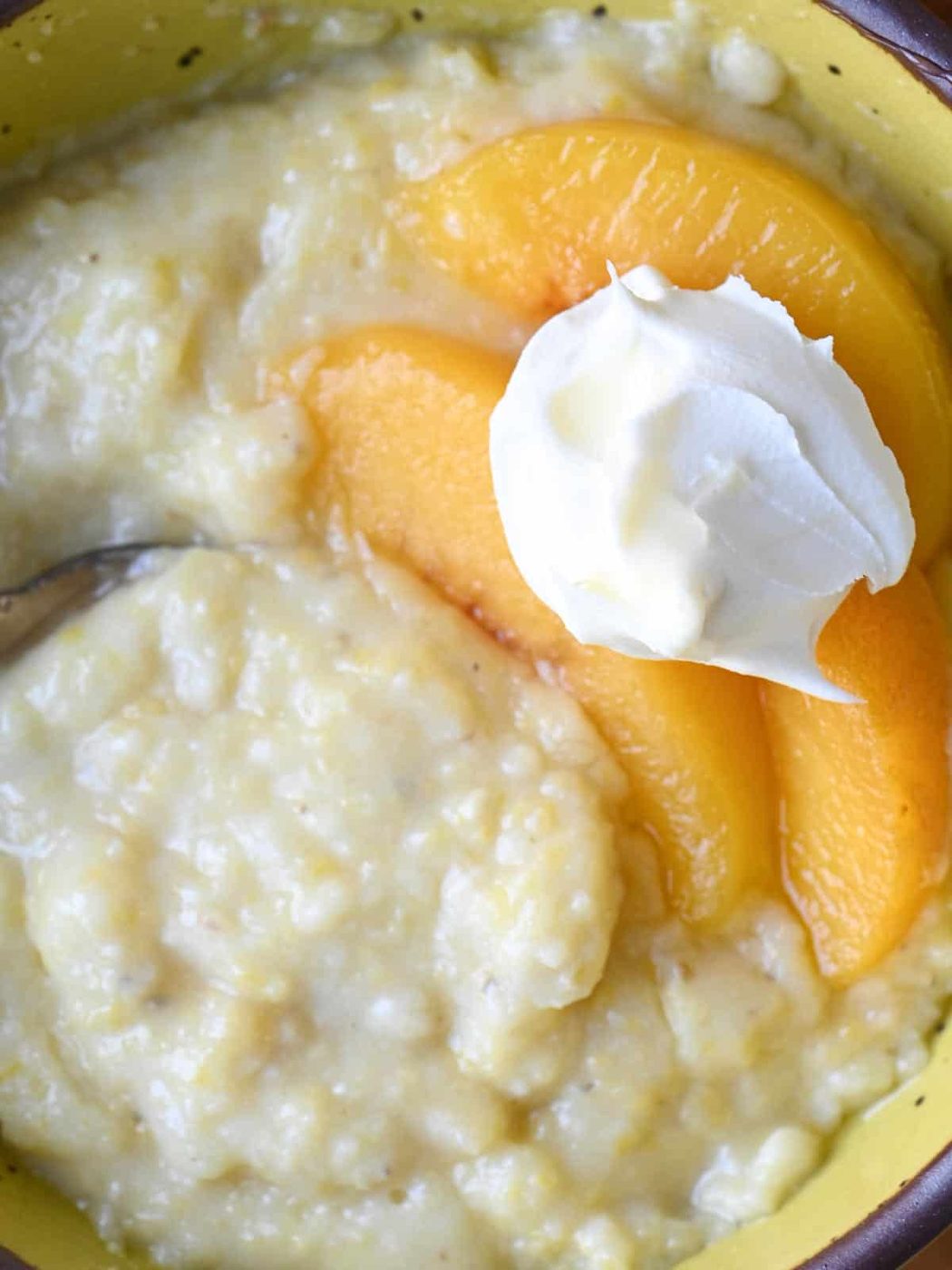 Overhead of creamy polenta with peaches and cream in a bow.