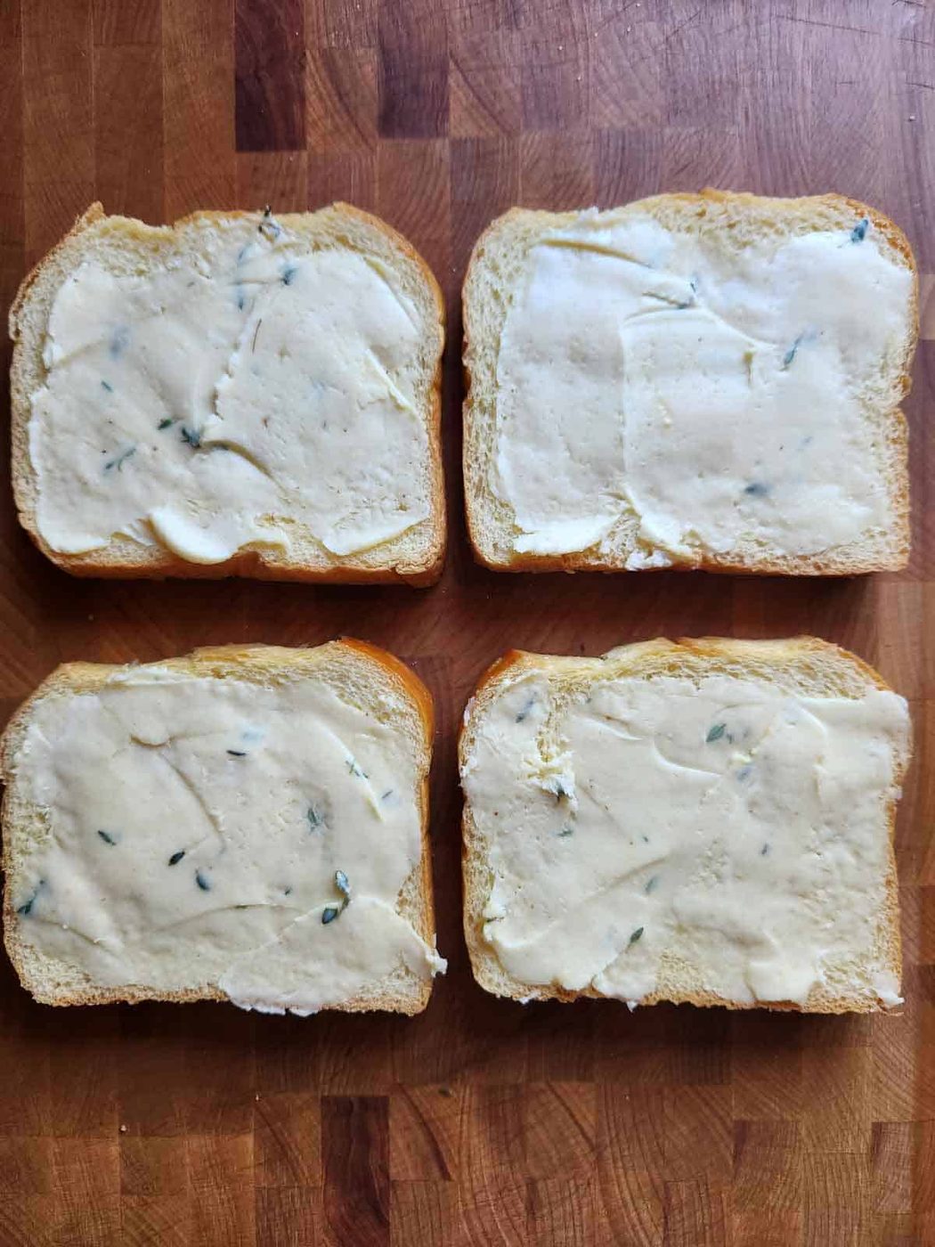 Four slices of buttered bread on a cutting board.