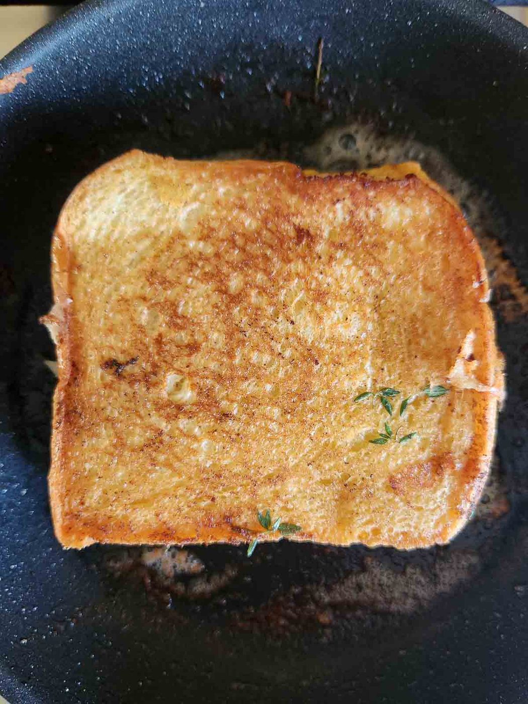 Grilled cheese cooking in a black skillet.