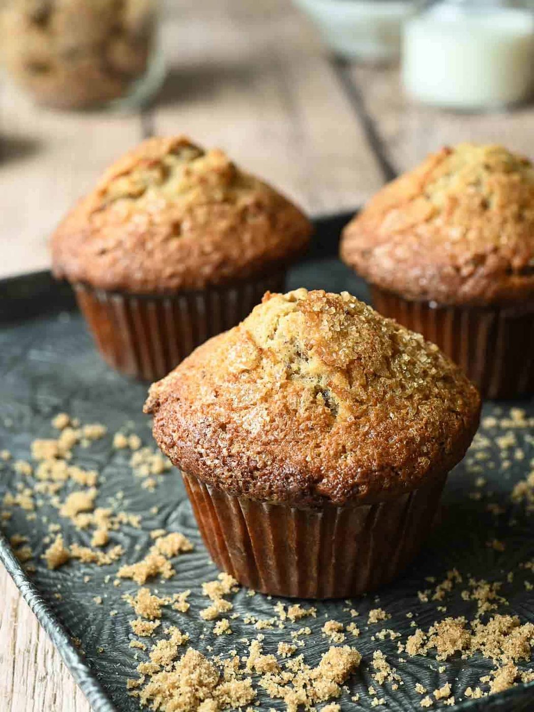 Close-up of date muffins on a metal tray with brown sugar in the background.
