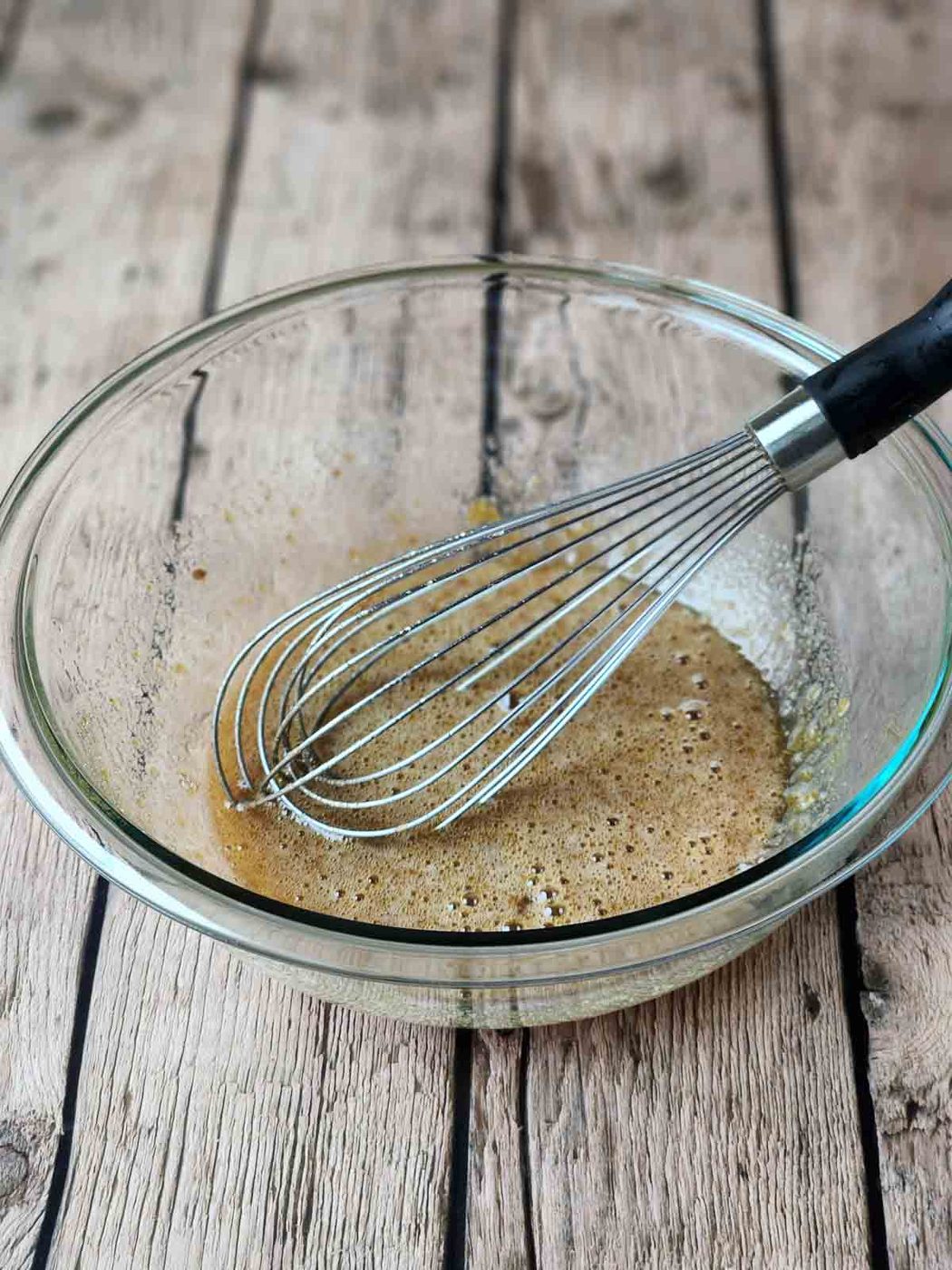 Wet ingredients for muffins in a clear bowl with a whisk.