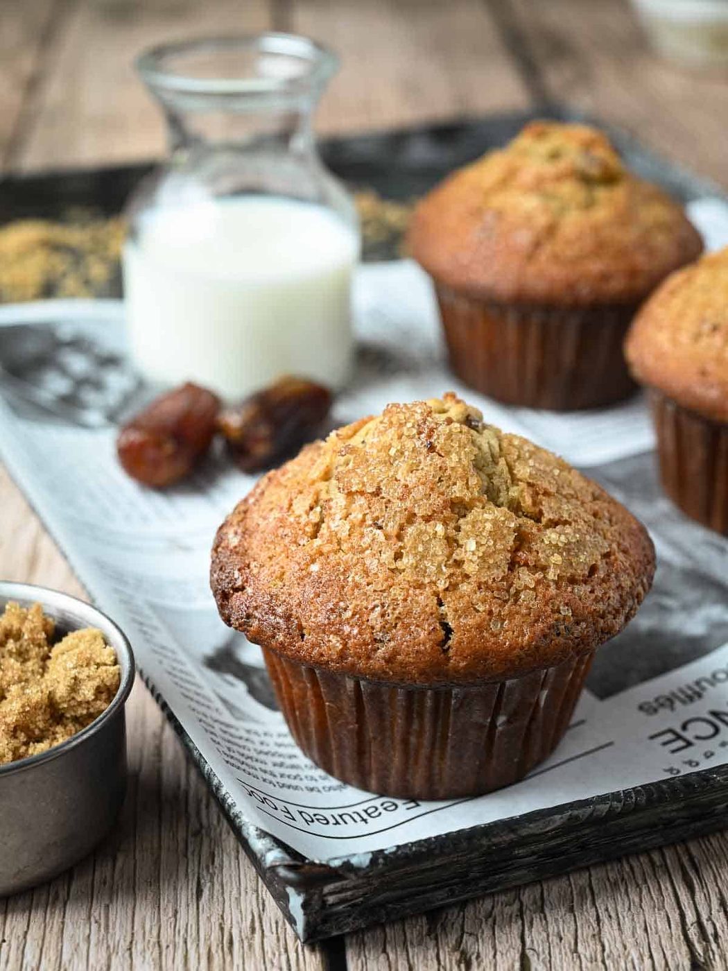 Close-up of a date muffin on a tray with wax paper and milk in the background.