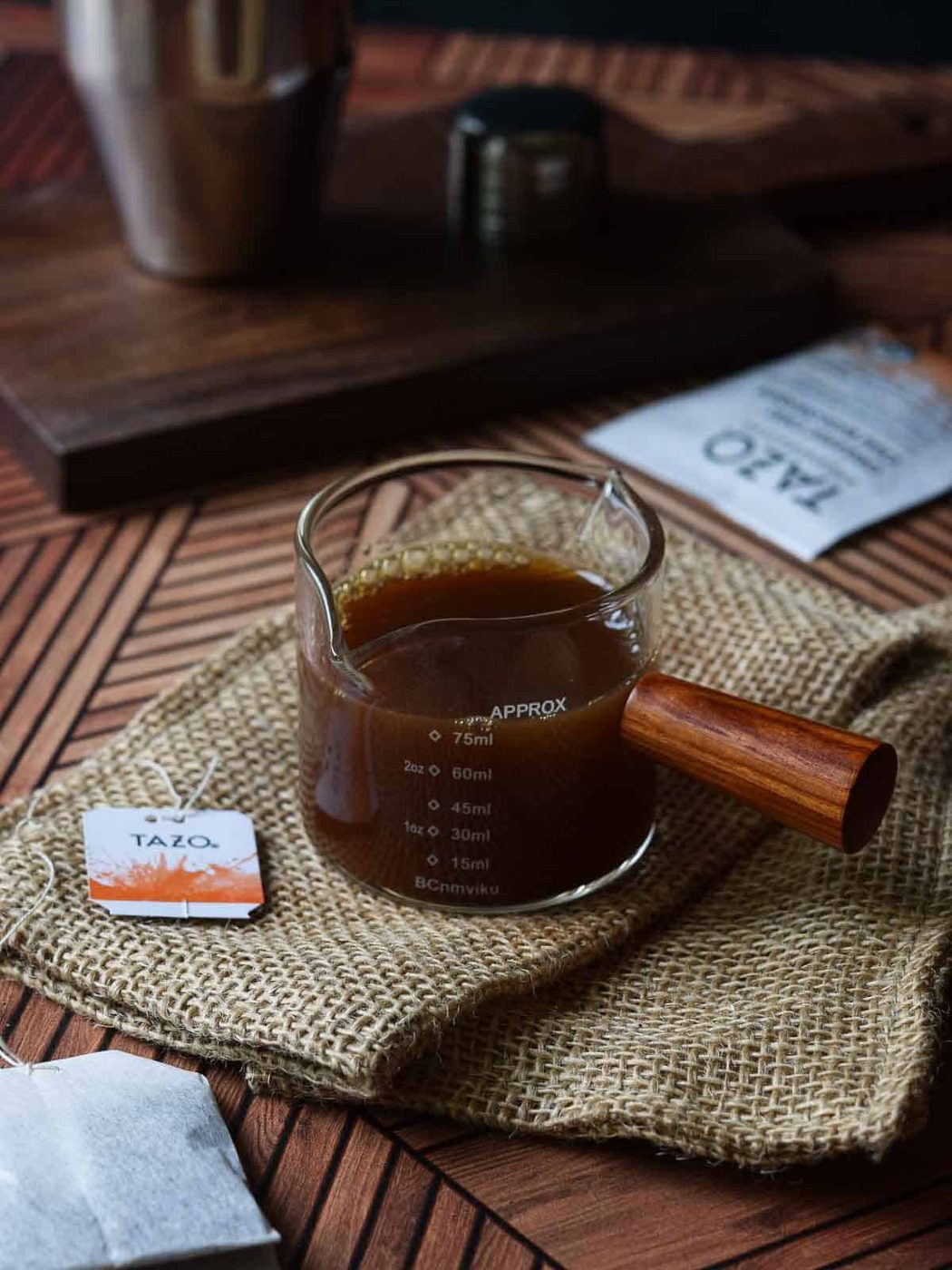 Chai concentrate in a small measuring cup on a brown surface.