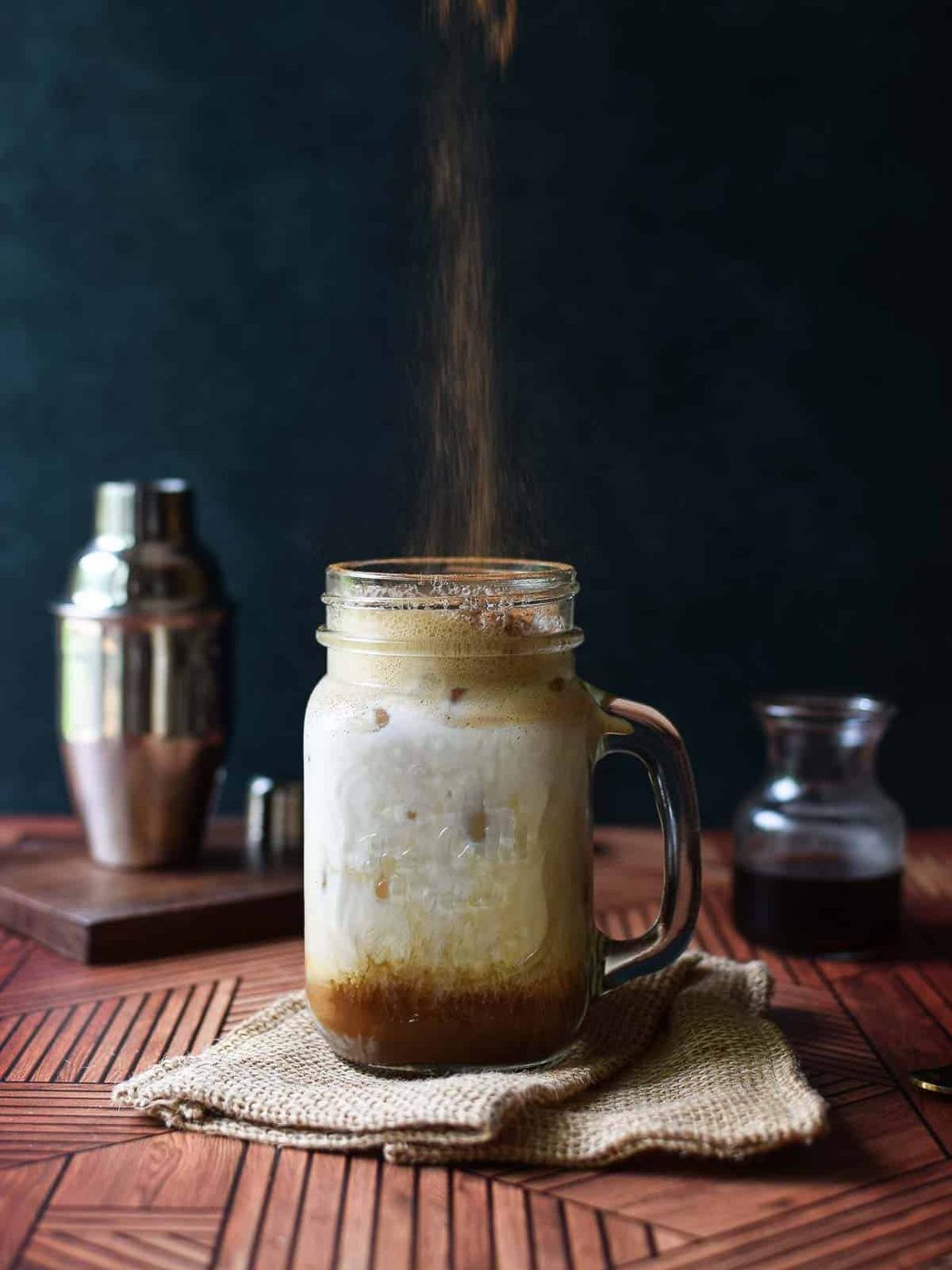 Cinnamon being dusted on a brown sugar chai iced tea.