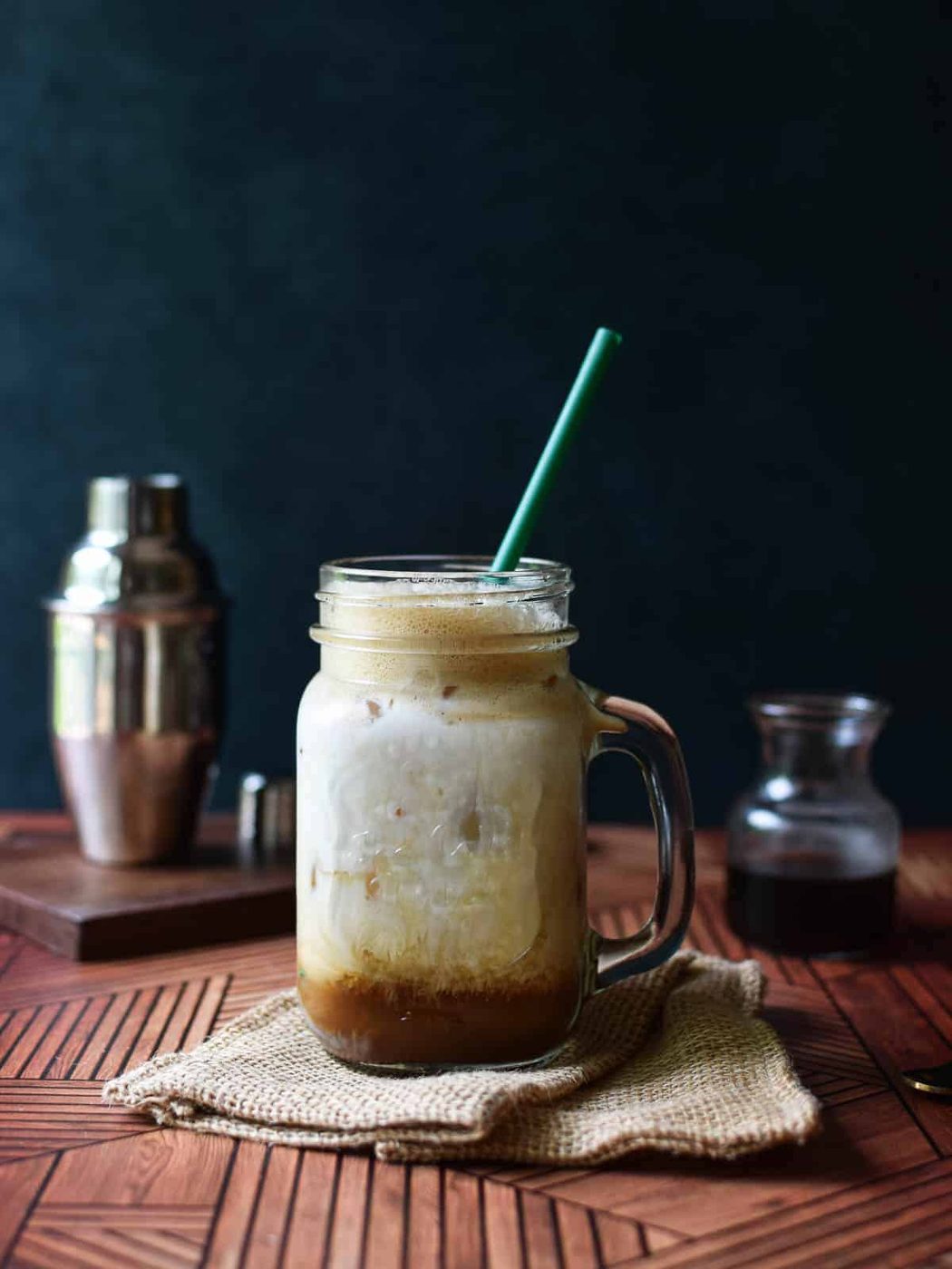 Brown sugar shaken chai tea in a glass mug with ilk and a green straw.