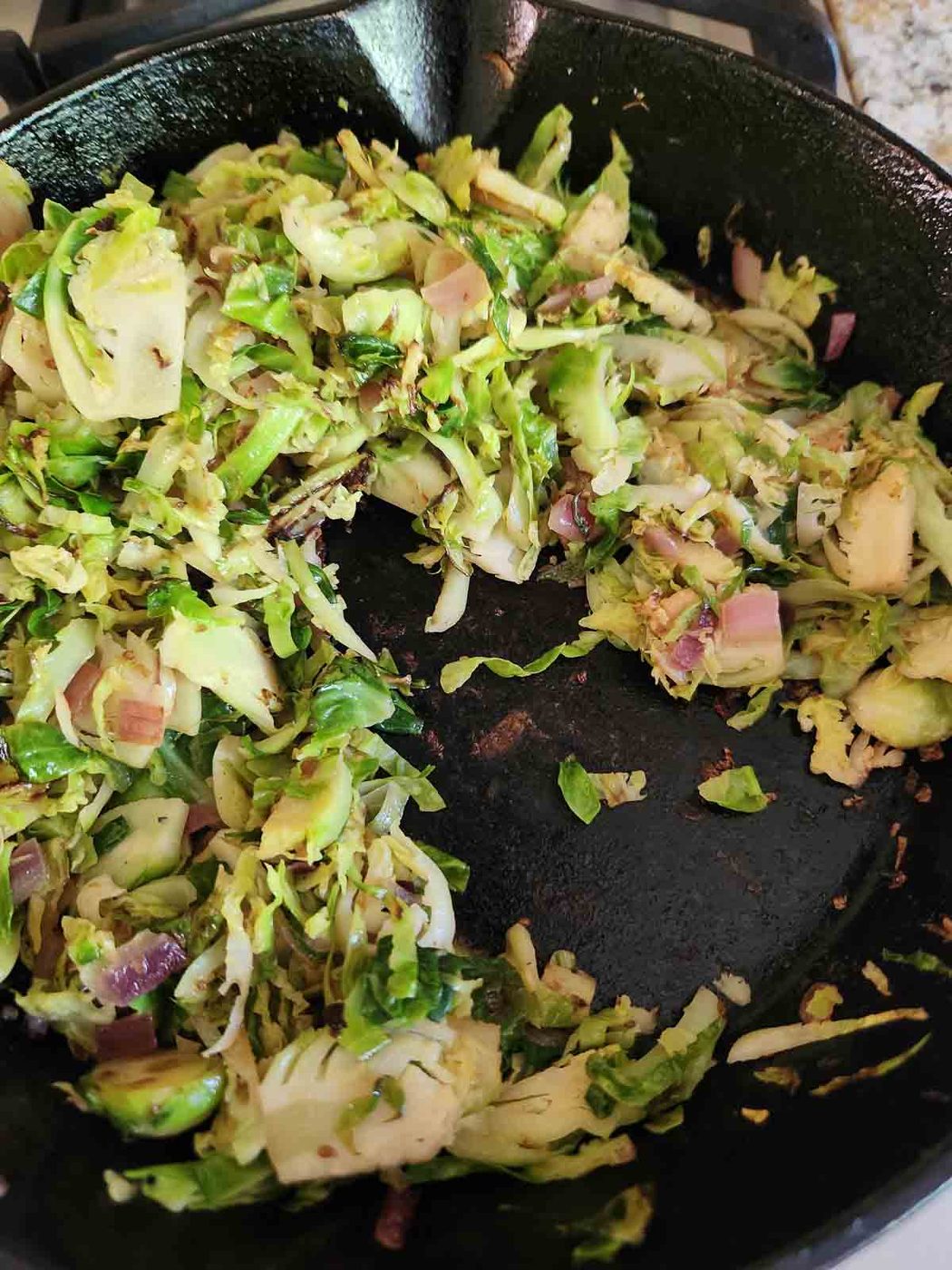 Cooked Brussel sprouts in a black skillet.