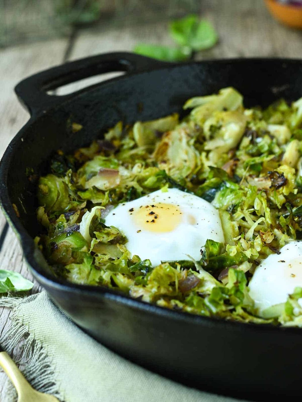 Brussel sprout hash in a black skillet with eggs.