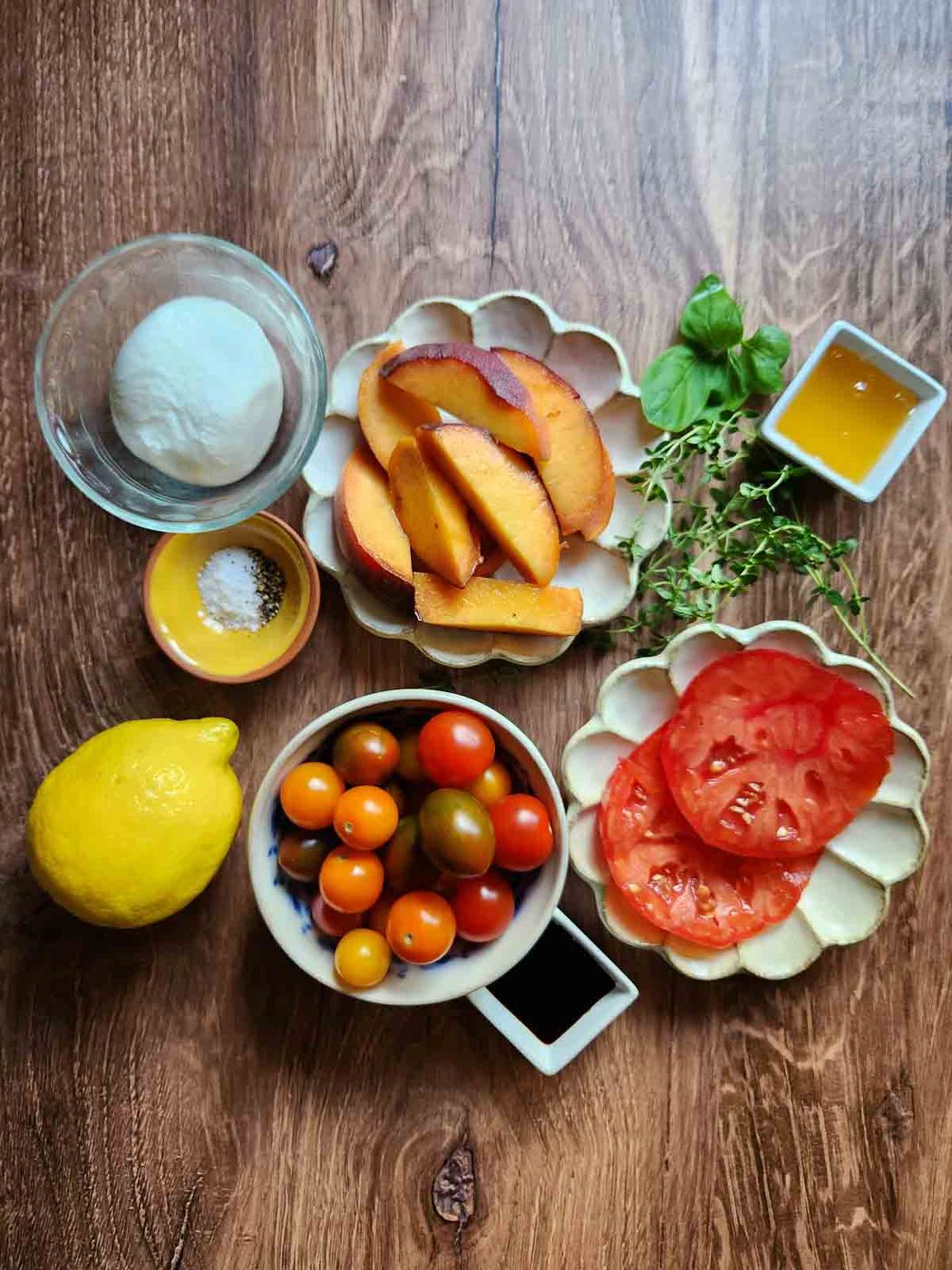 Ingredients for burrata peach salad on a wood background.