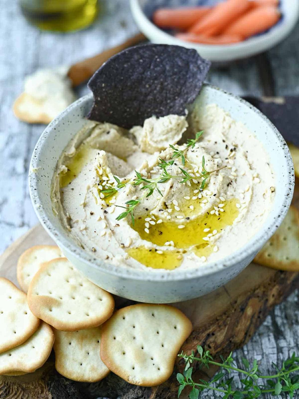 Chip being dunked into a bowl of bean hummus.