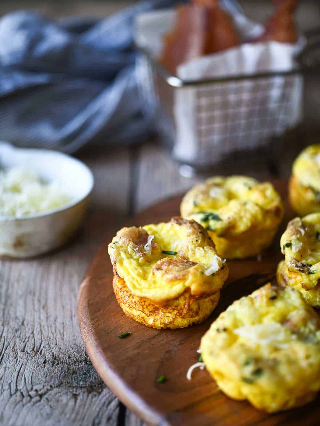 Egg bites on a wood board with bacon and cheese.
