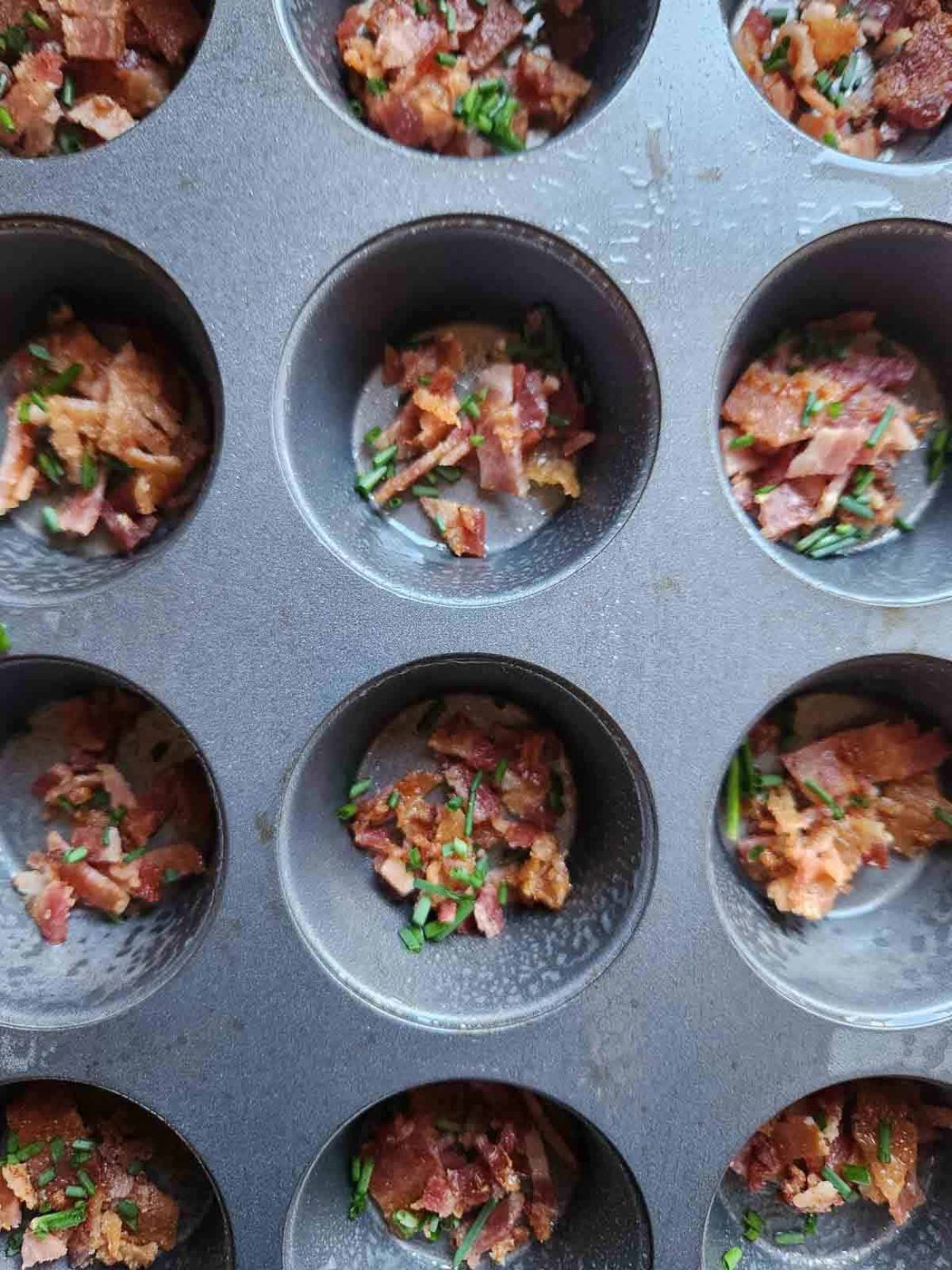 Bacon and chives in a muffin tin.