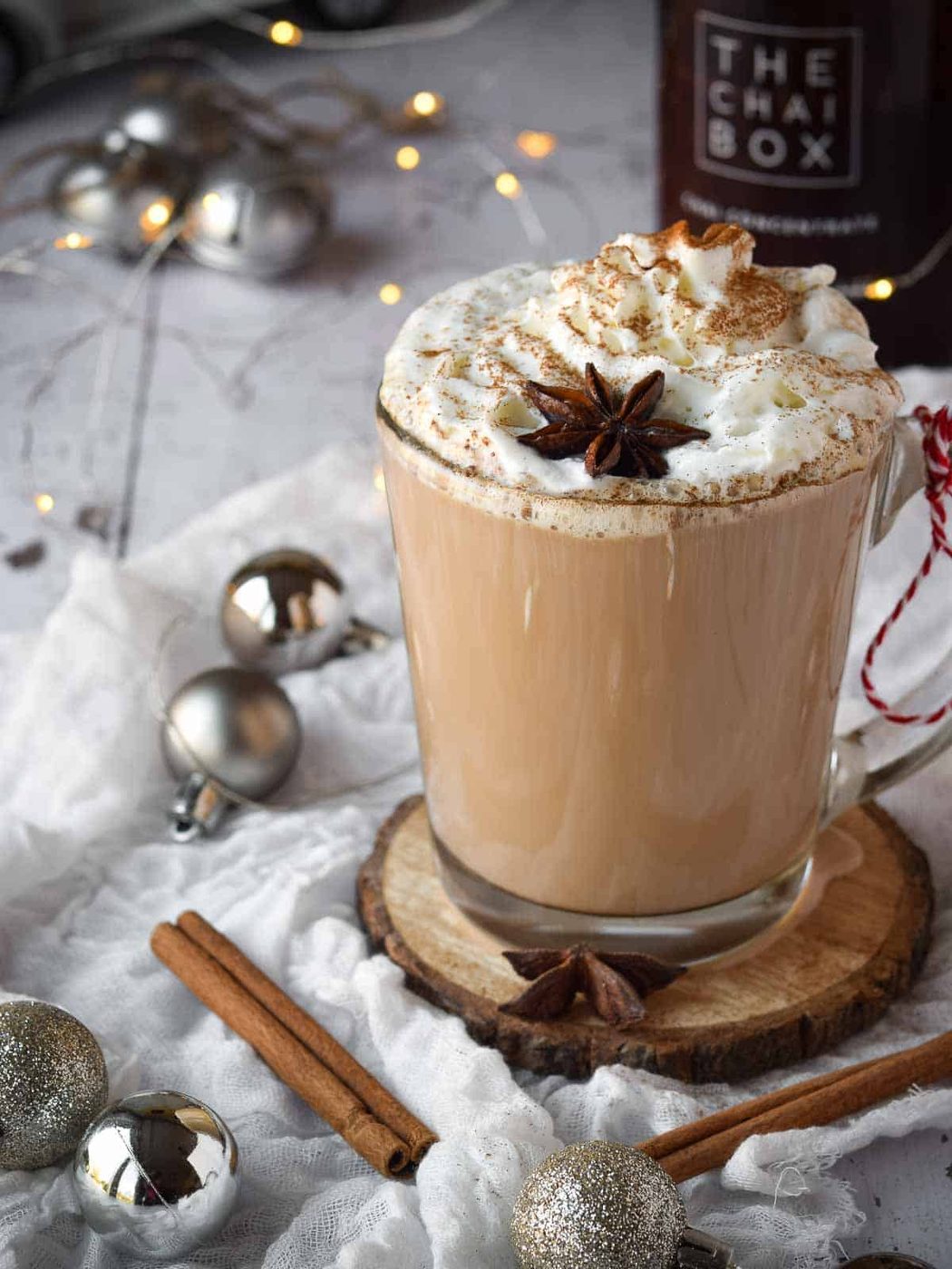 Chai eggnog latte in a clear mug with whipped cream and spices on top.