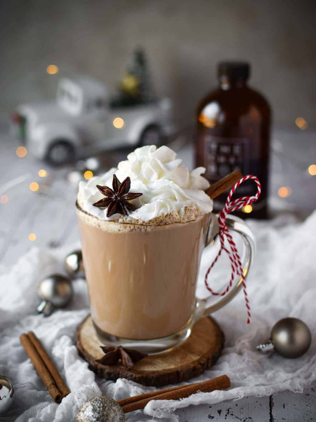 Chai eggnog latte in a clear mug with twinkle lights and ornaments around it.