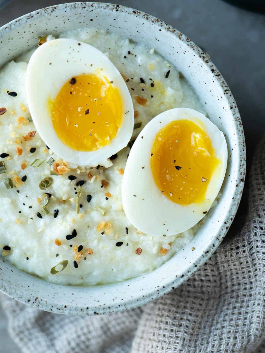 Overhead of a bowl of grits with 2 jammy eggs split open on top.