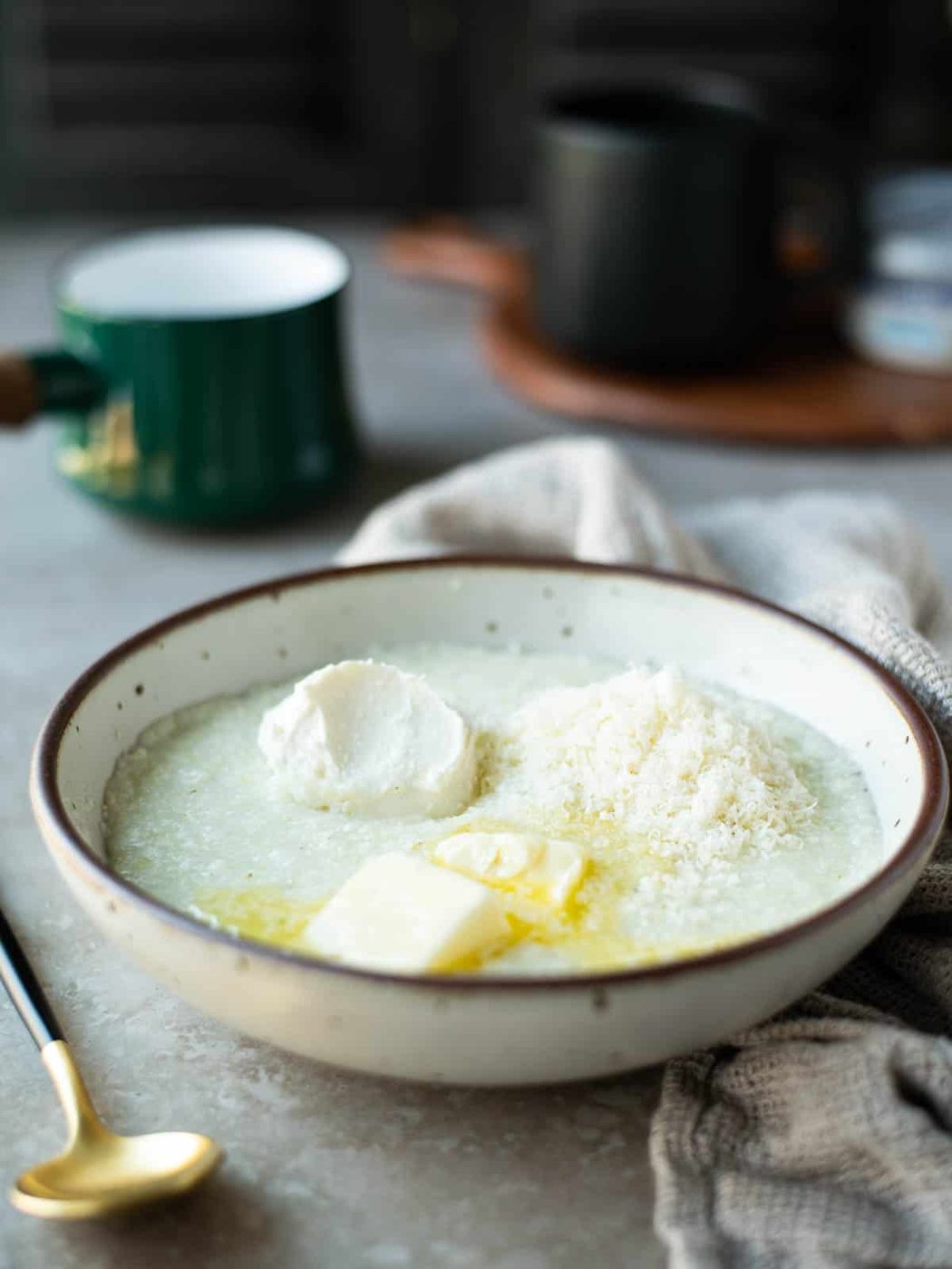 Grits with cream cheese, butter and parmesan in a beige bowl.