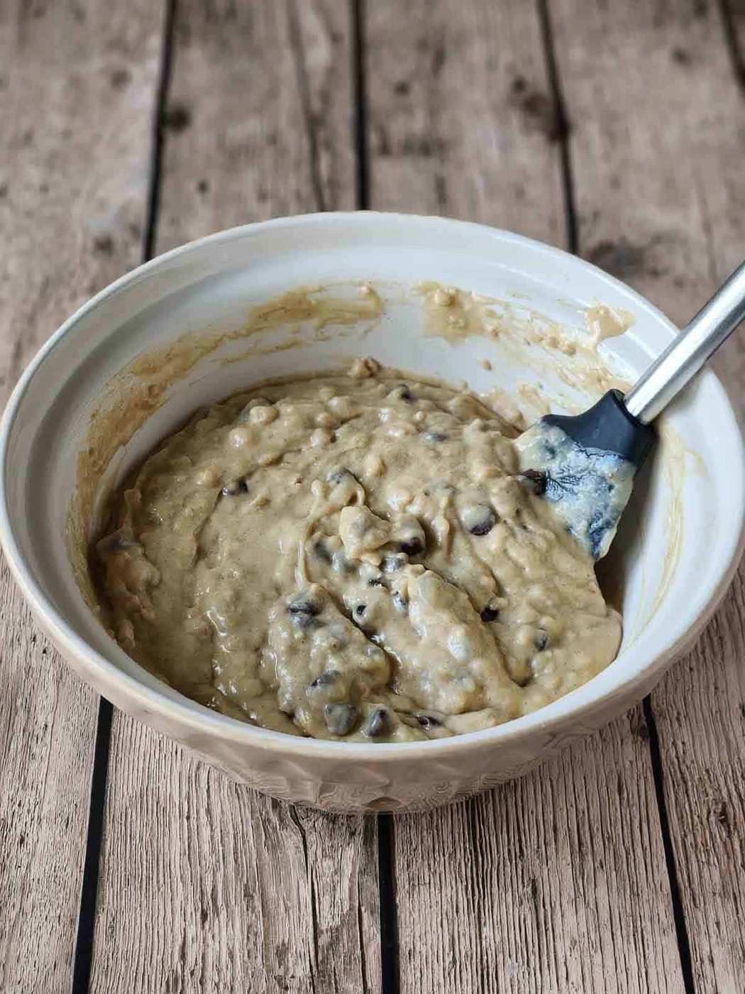 Cake batter with chocolate chips in a beige bowl.