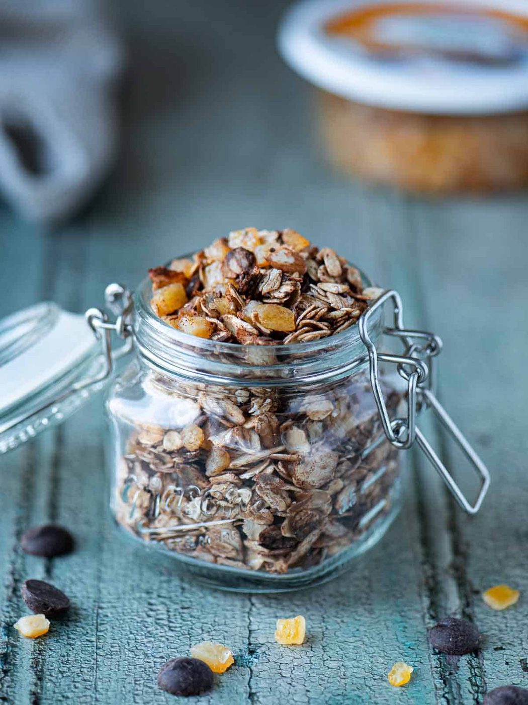 Chocolate muesli in a clear mason jar on a blue surface.