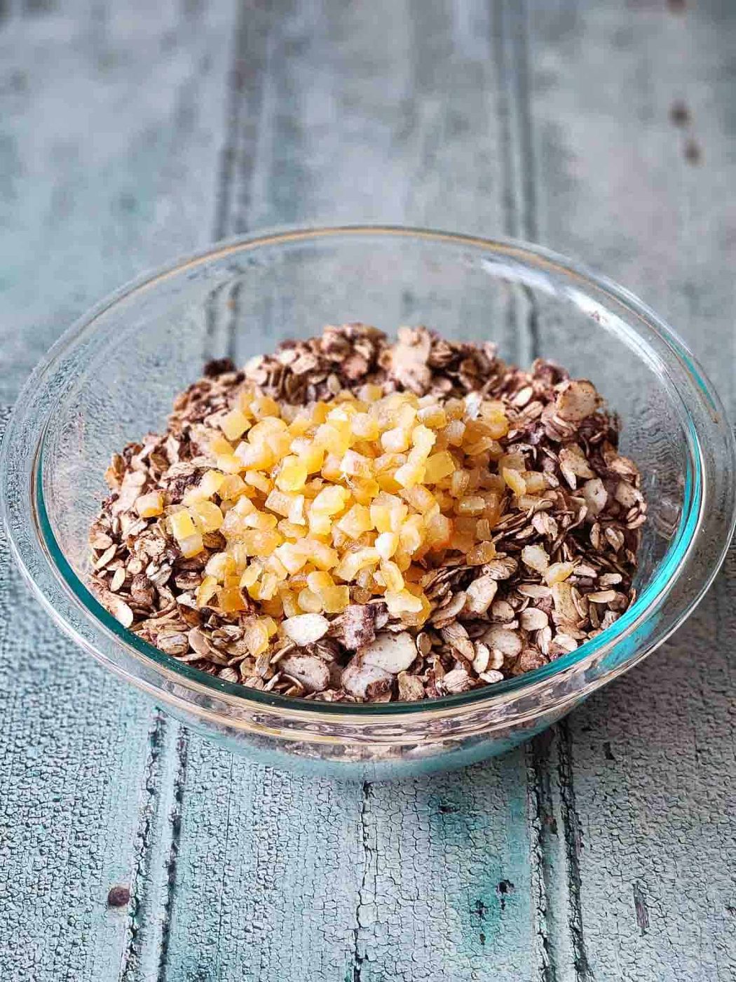 Chocolate muesli in a clear bowl with candied orange on top.