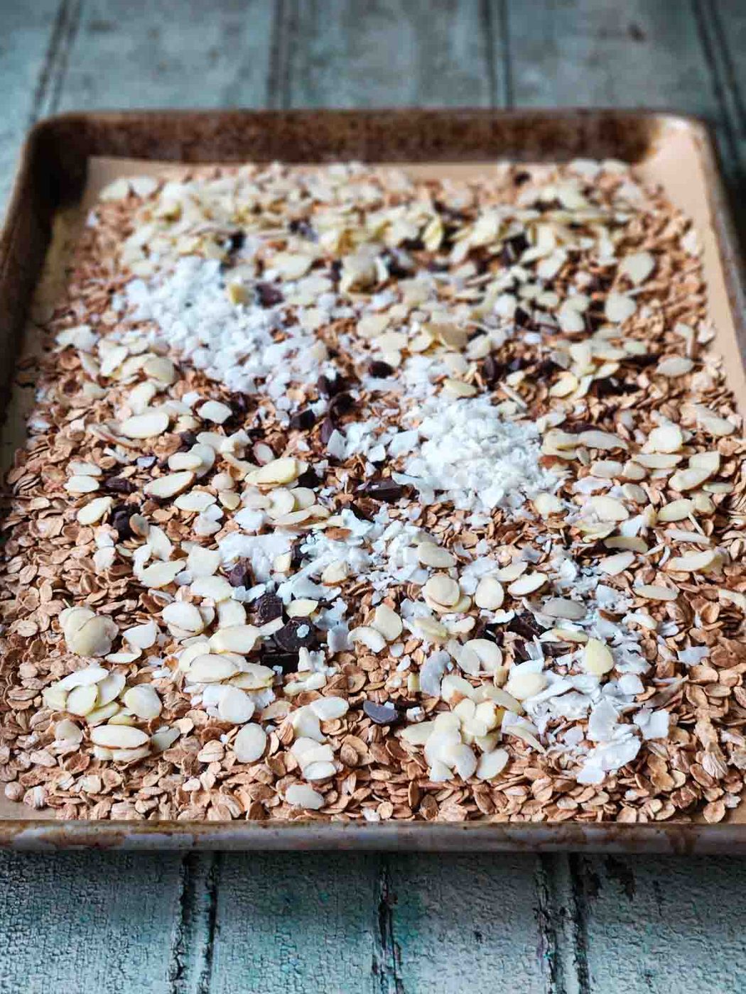 Toasted oats, coconut and chocolate on a baking sheet.