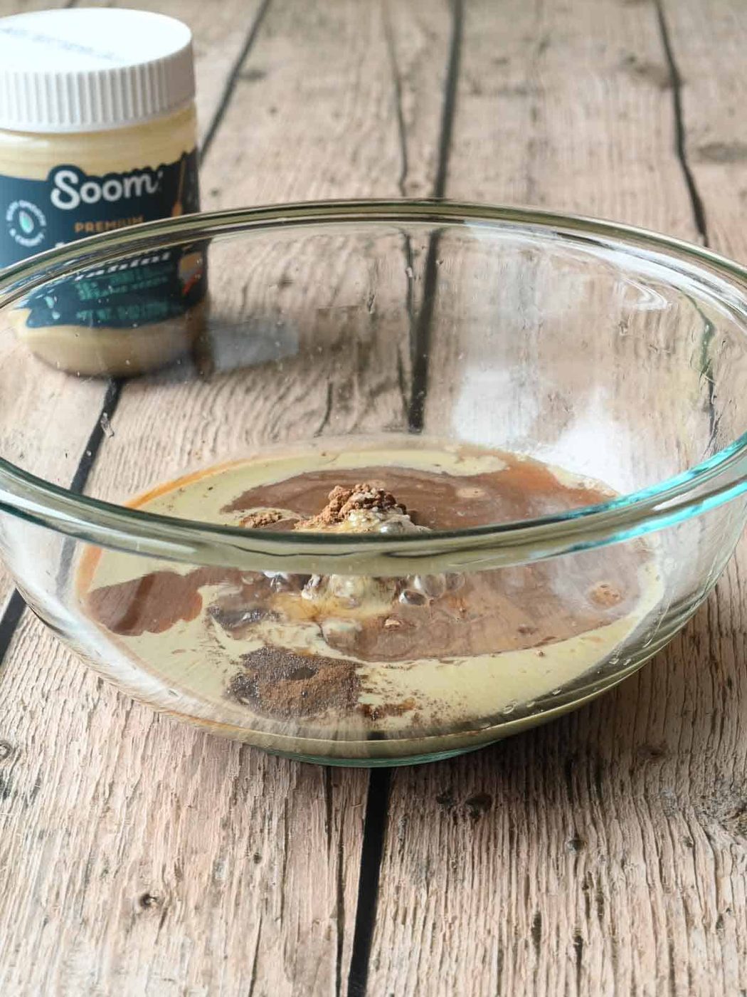 Ingredients in a clear mixing bowl for tahini chocolate.